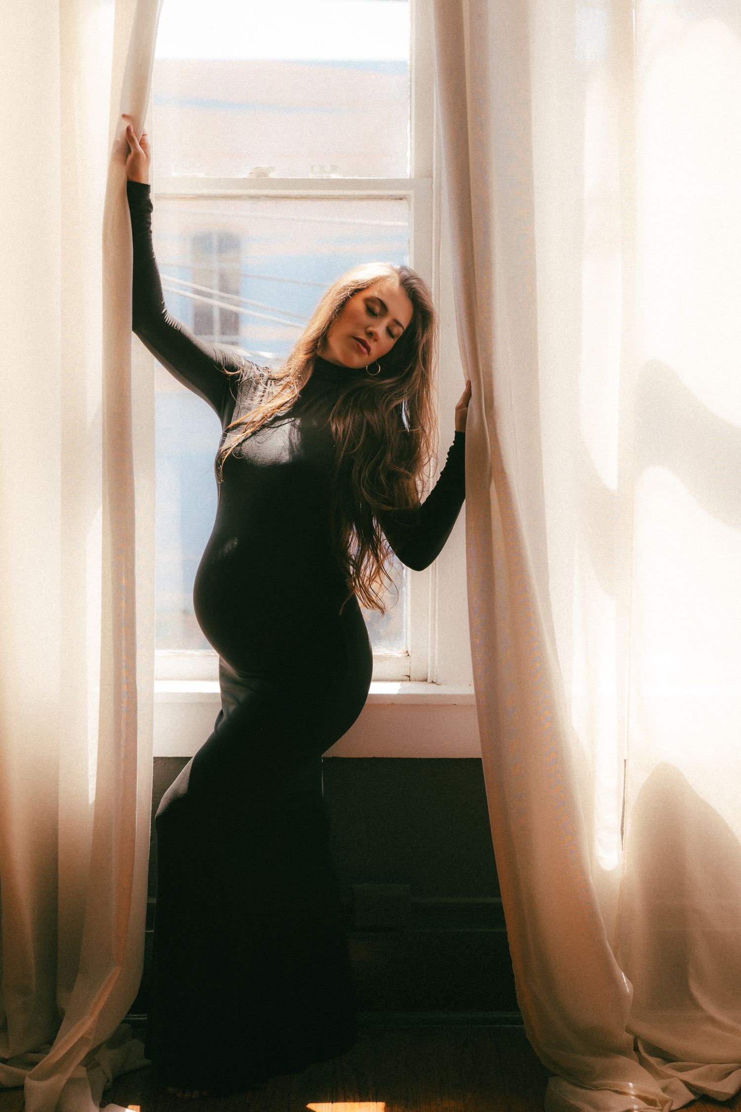 Woman in black dress dances gracefully by window with sheer curtains in artistic photo sequence.