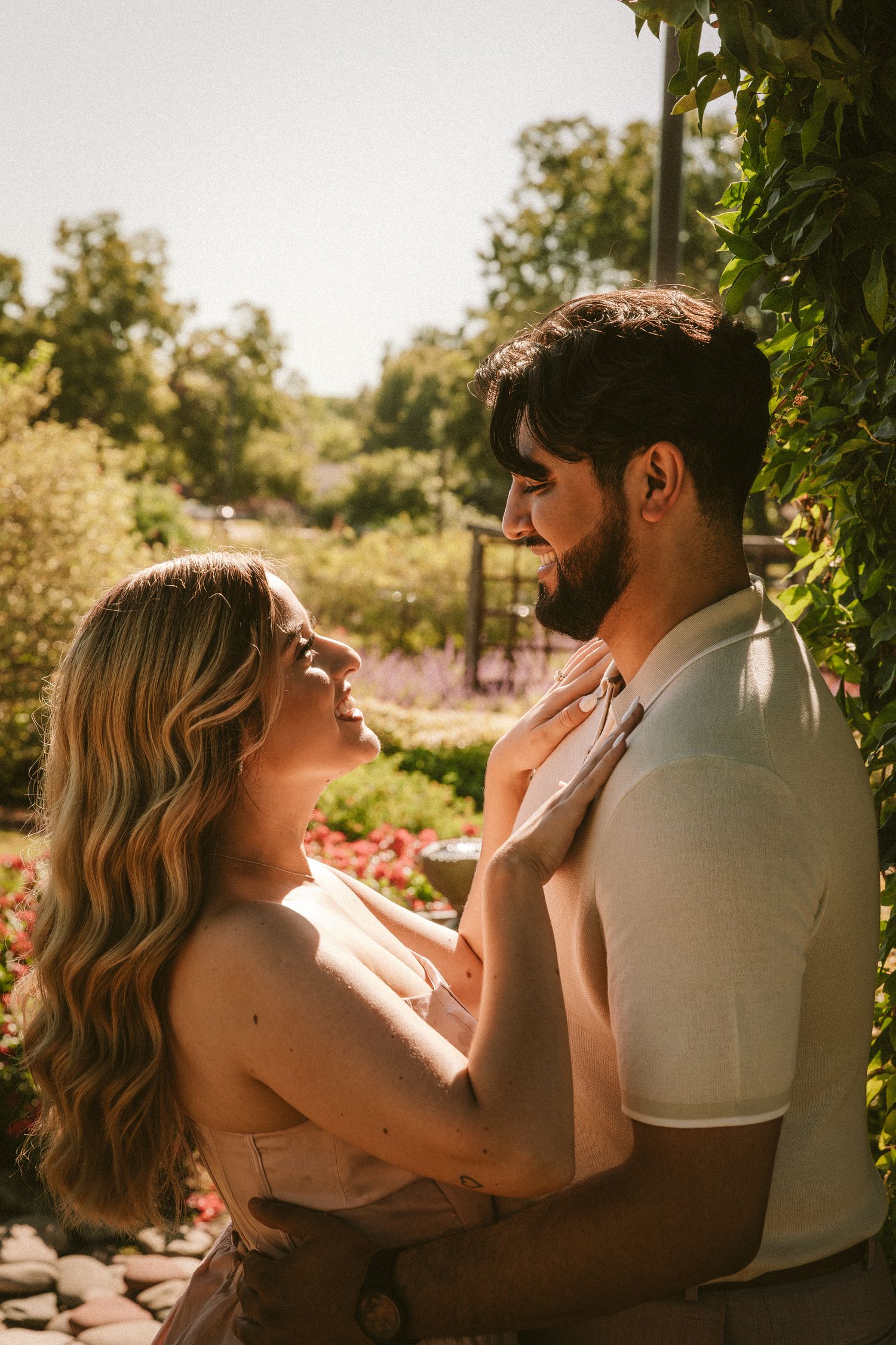 Couple embracing tenderly on outdoor patio with lush greenery in background.