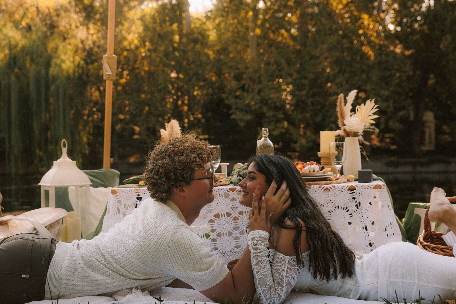A romantic couple embraces during golden hour in a dreamy outdoor setting with glowing sunlight filtering through trees.