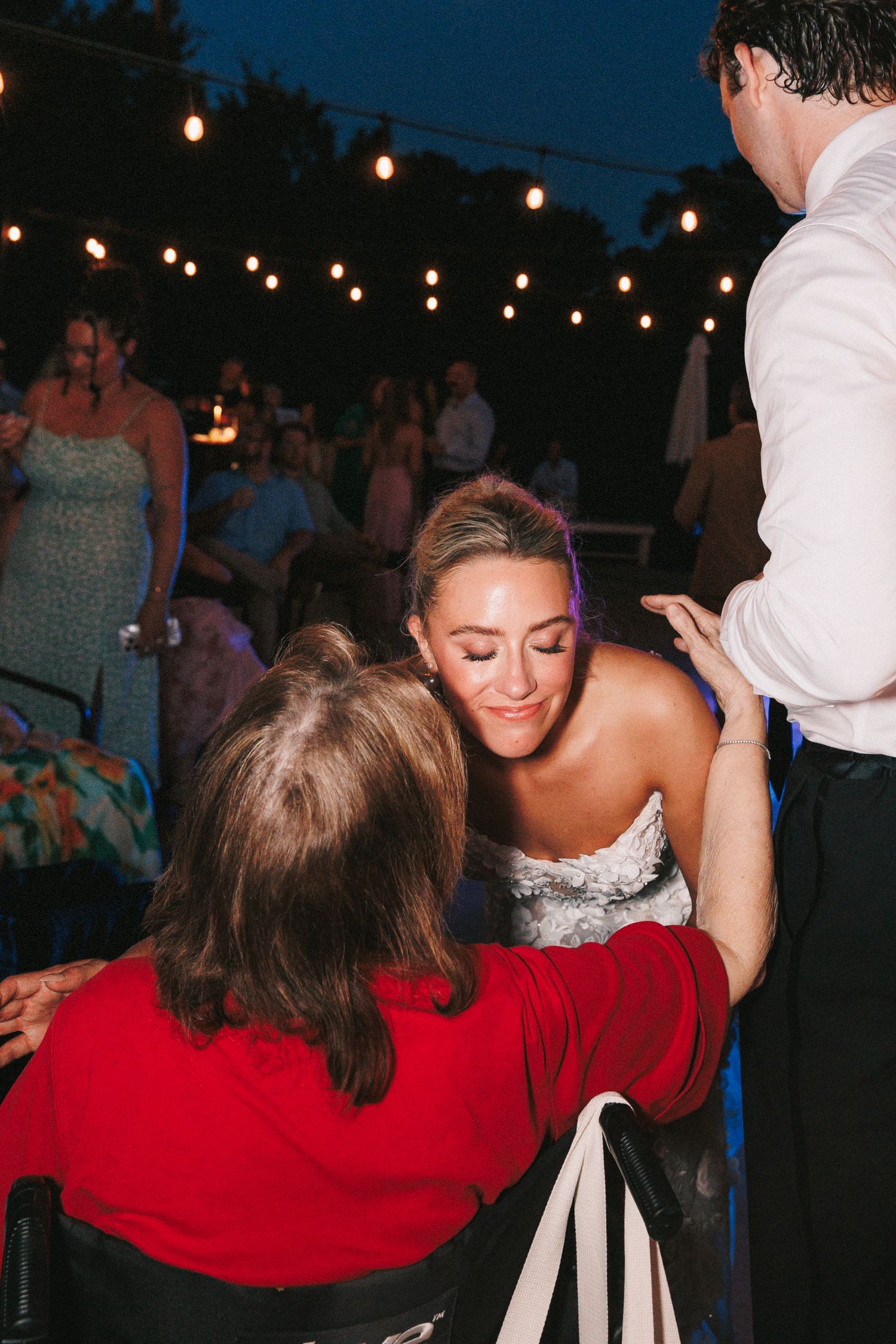 A wedding reception dance party at night with string lights overhead.