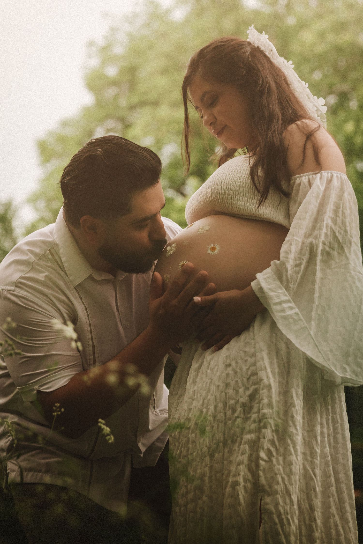 Intimate maternity photo series of couple in soft natural light showing affection and anticipation while kissing belly.