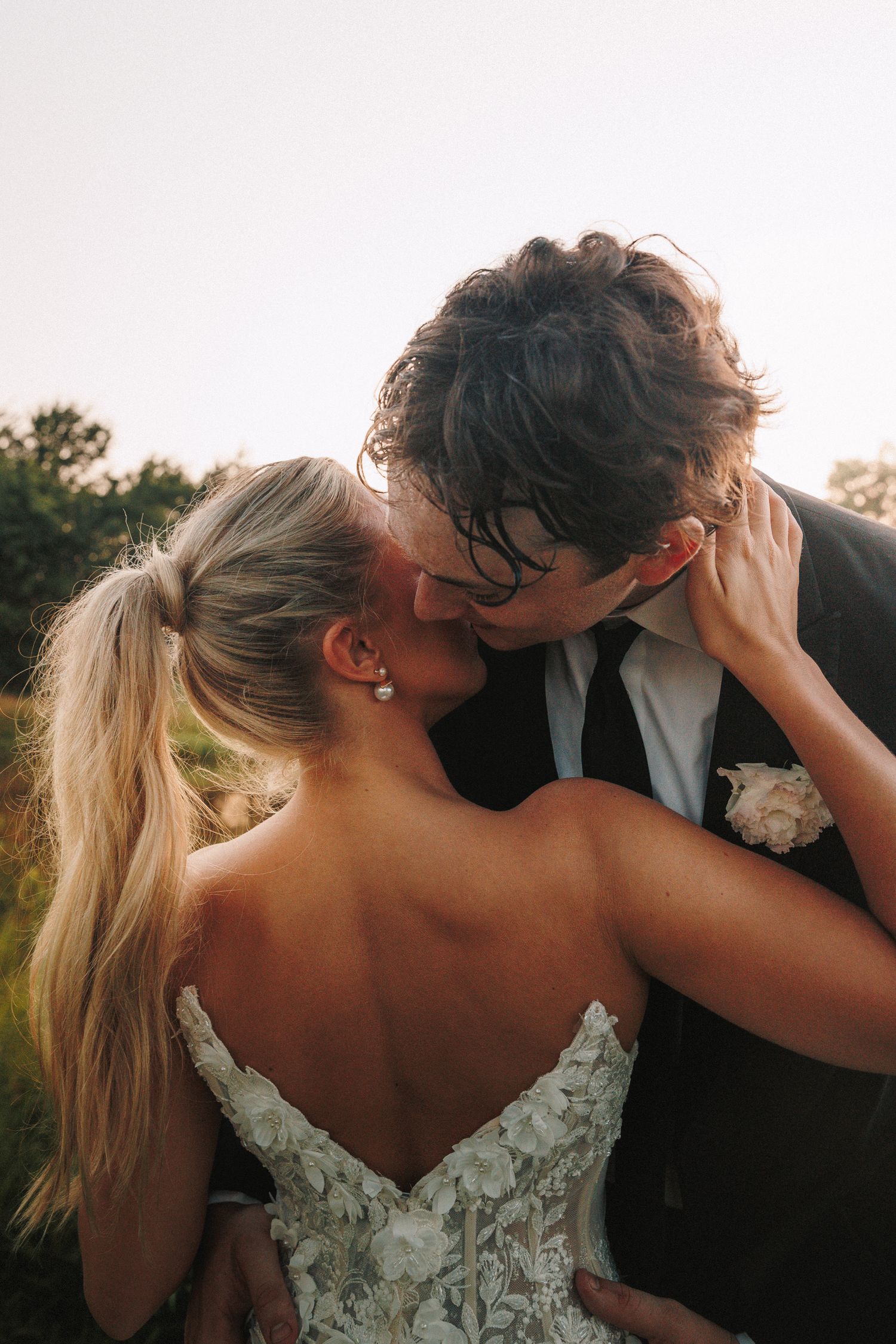 A romantic wedding moment captured at sunset with the bride wearing a lace dress.