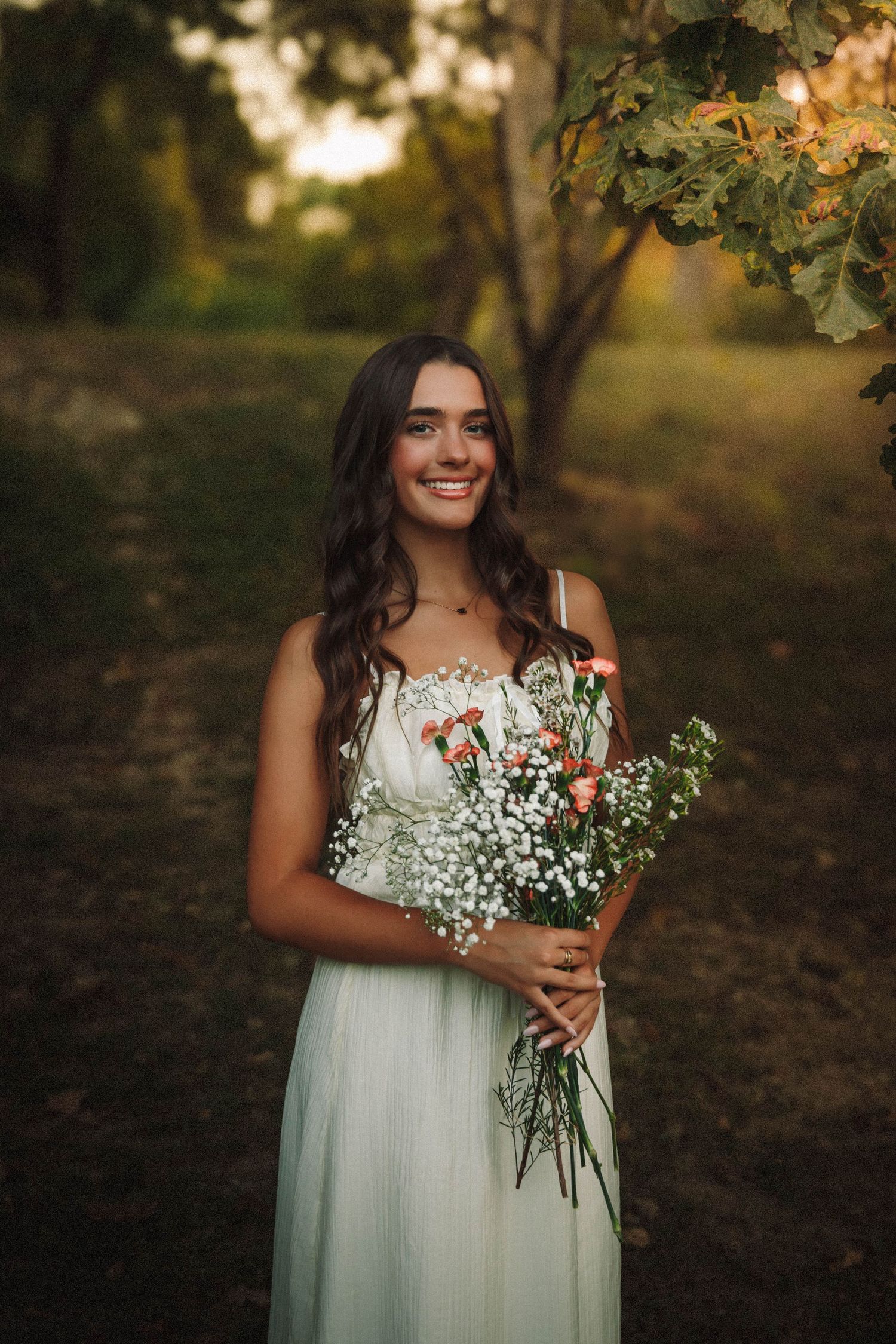 A series of outdoor portraits showing someone in a flowing white dress holding delicate baby's breath flowers at golden hour.