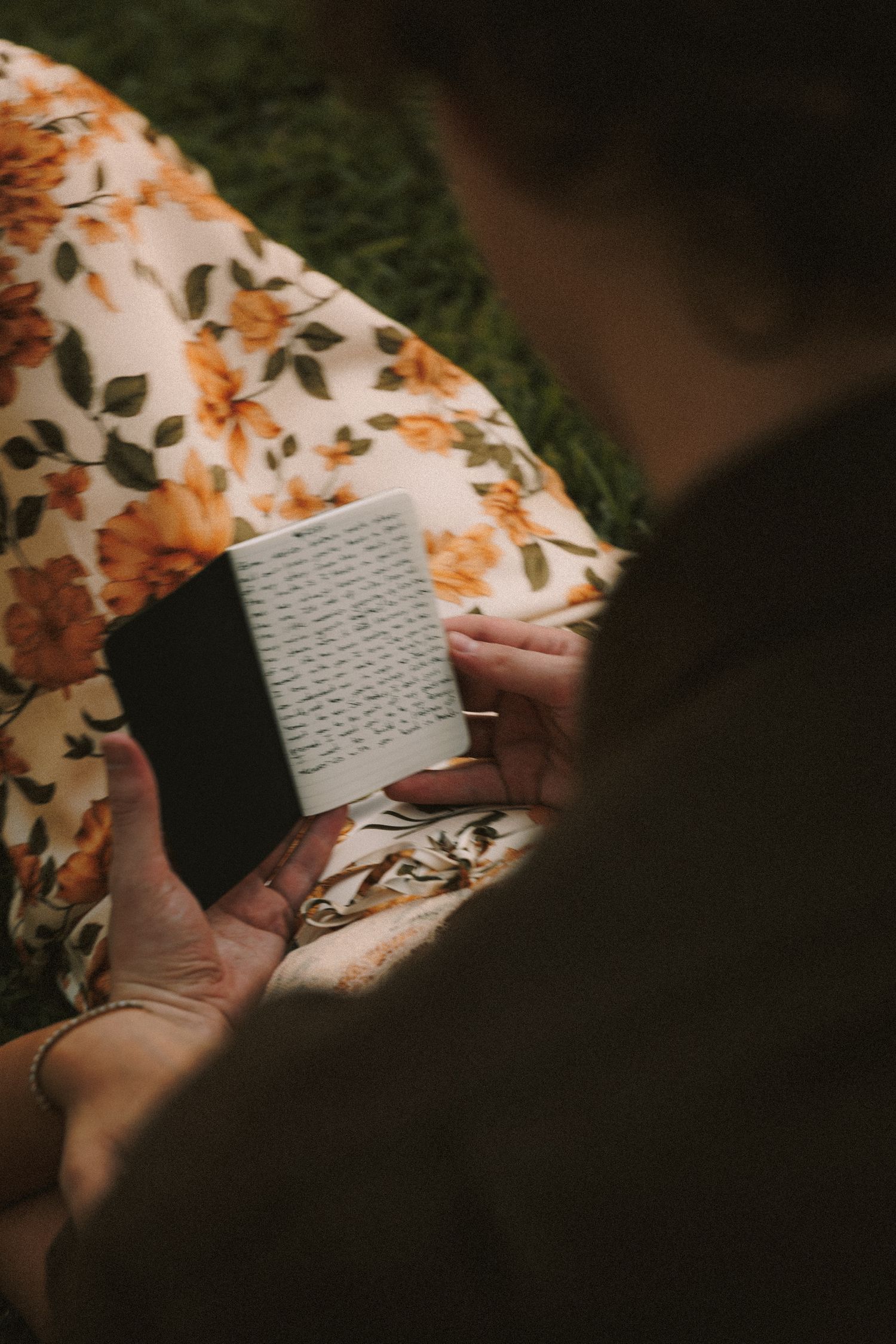 Close-up shot of hands holding handwritten letters against a floral patterned fabric background.
