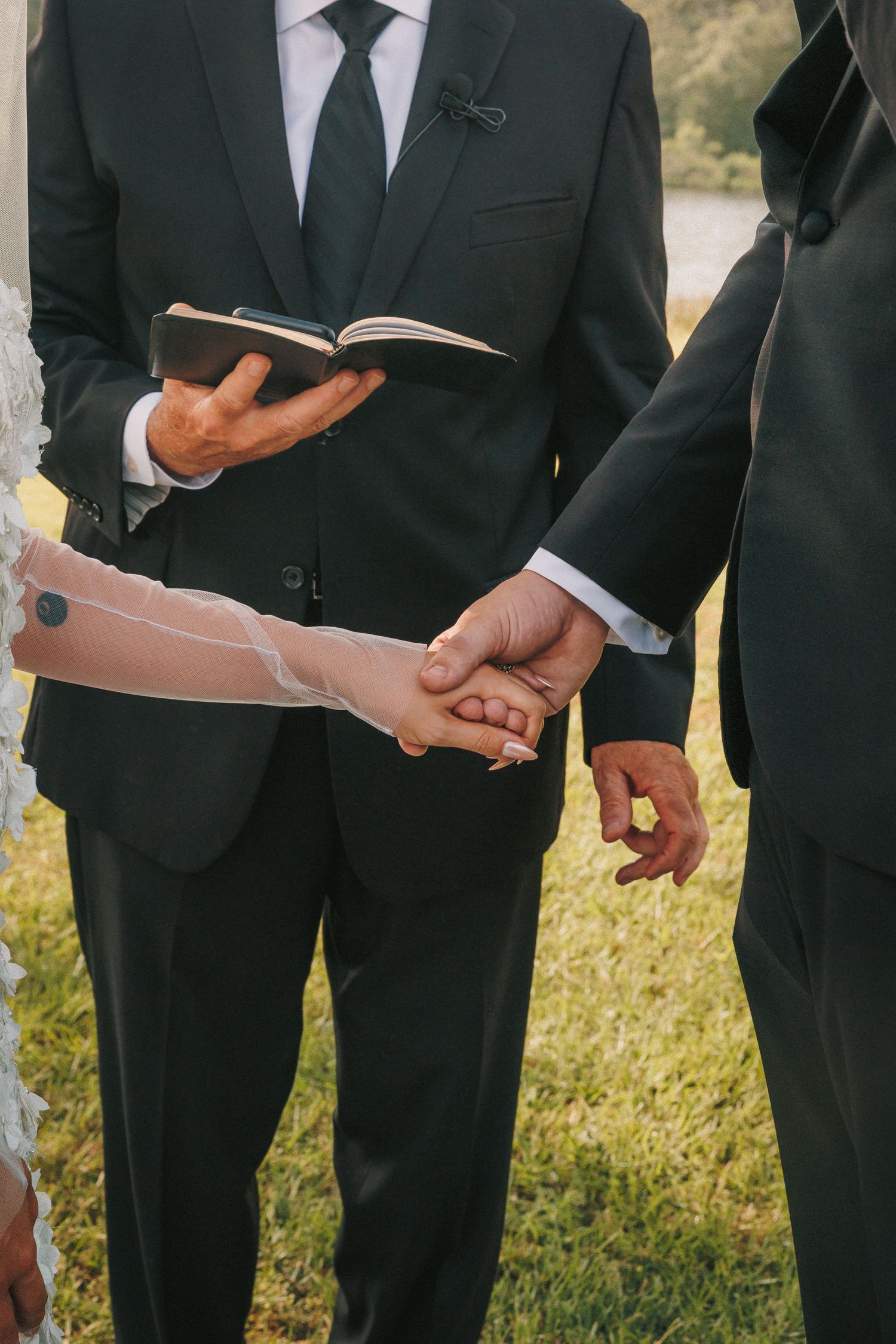 Detail shot of men in black suits holding ceremony programs outdoors.