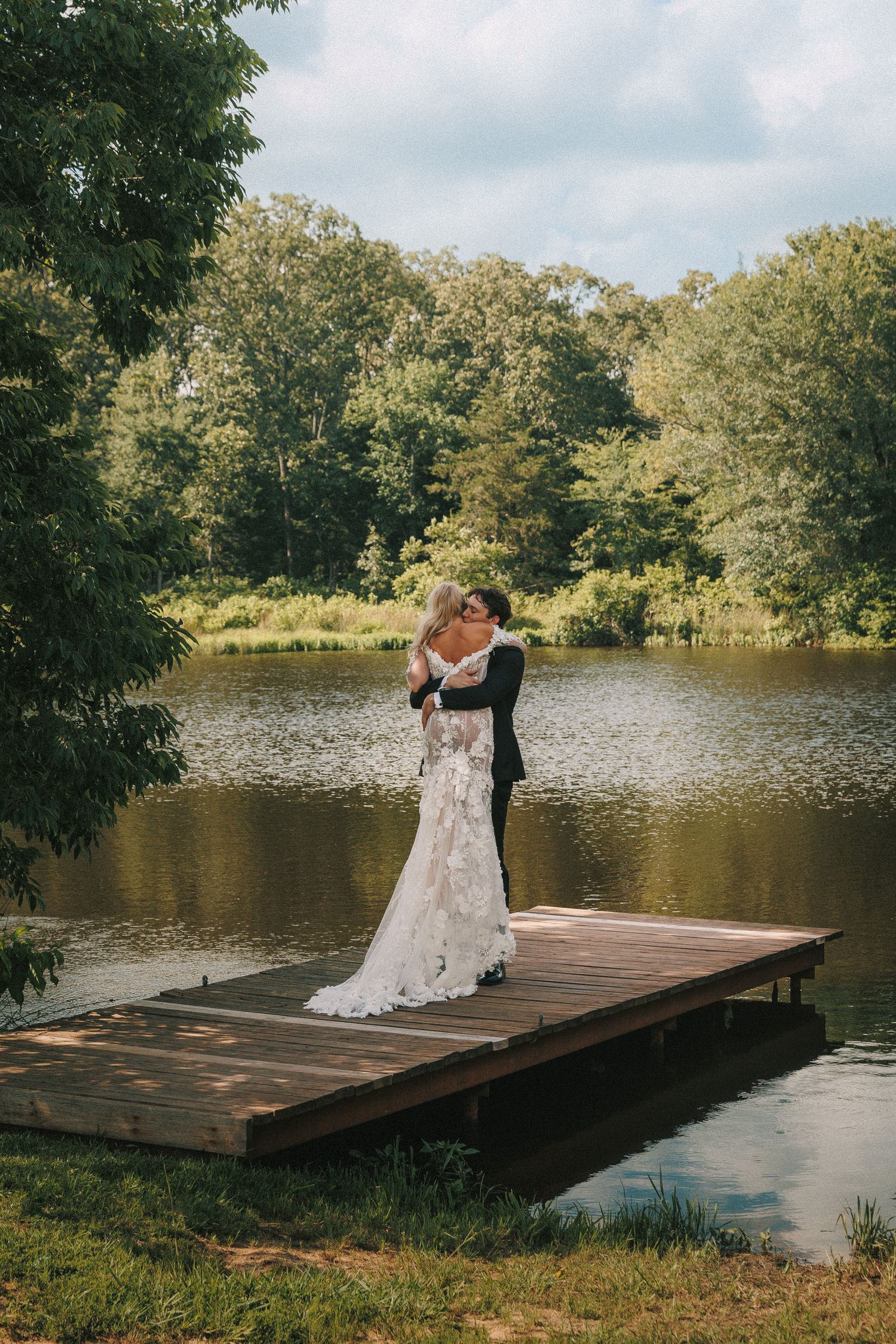 A romantic wedding photoshoot series on a wooden dock by a serene lake surrounded by lush trees.