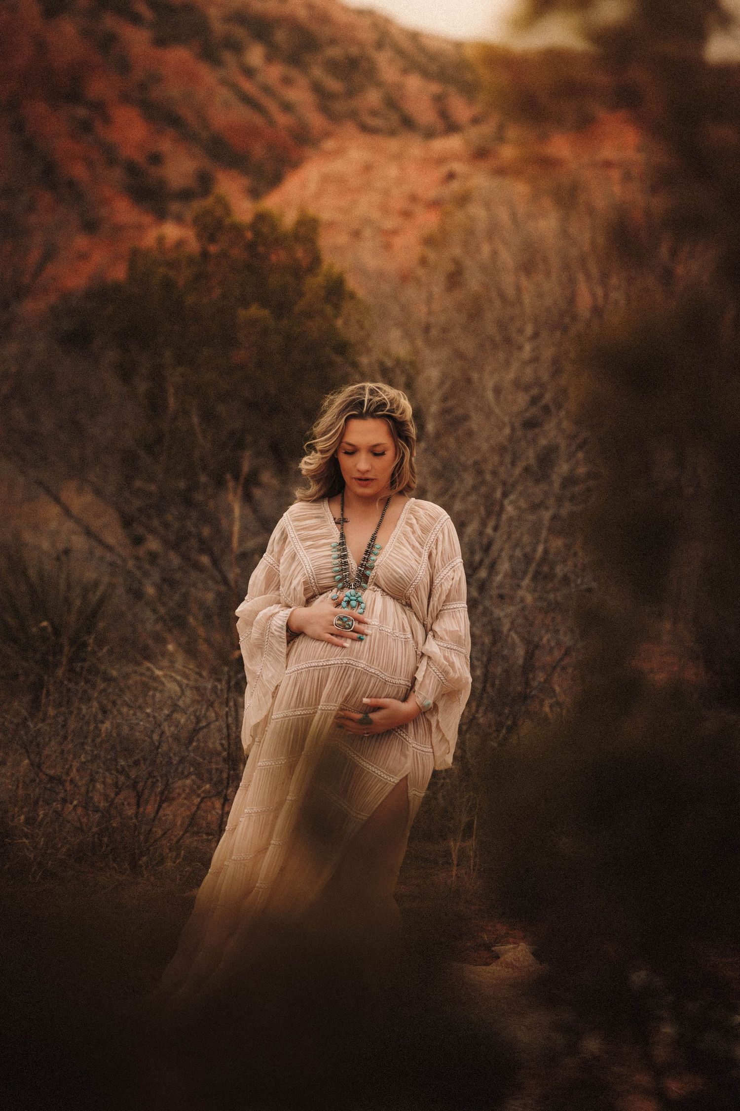 Woman in white vintage dress holds teacup in autumn forest setting during golden hour photography session.