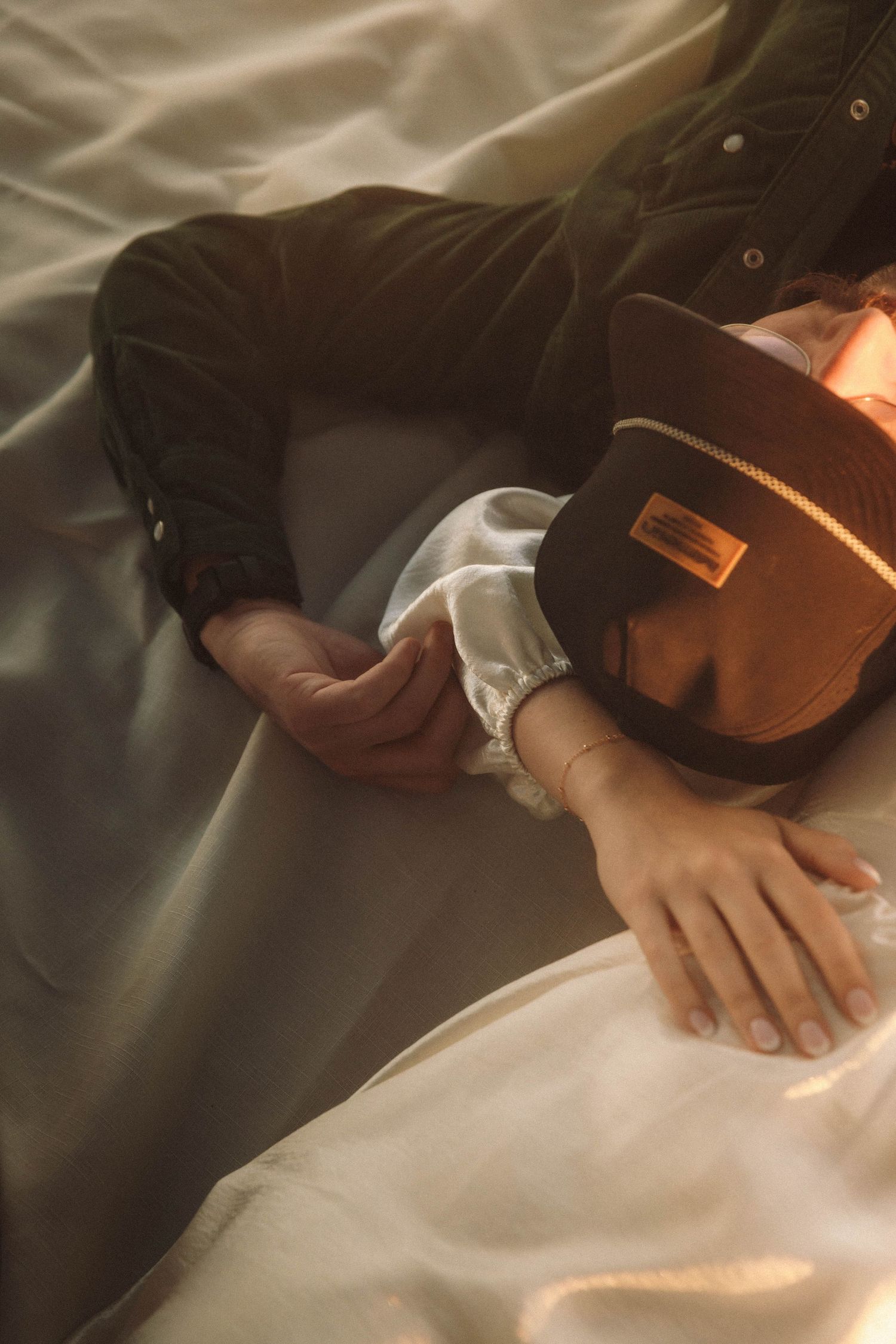 Gentle hands rest on soft white fabric creating an intimate and peaceful composition.
