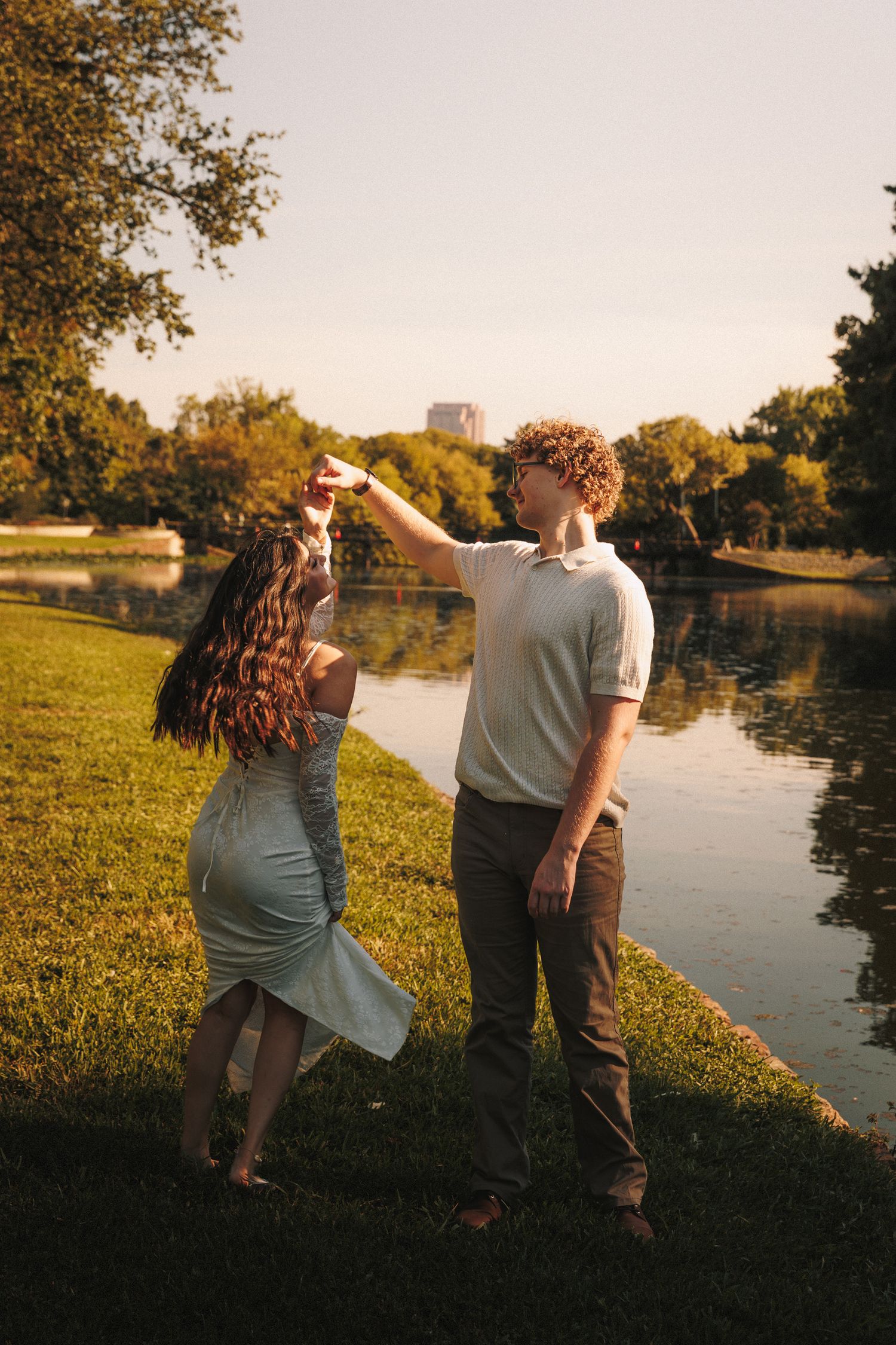 A couple enjoys a romantic sunset moment by a tranquil lake with autumn trees creating a golden backdrop.
