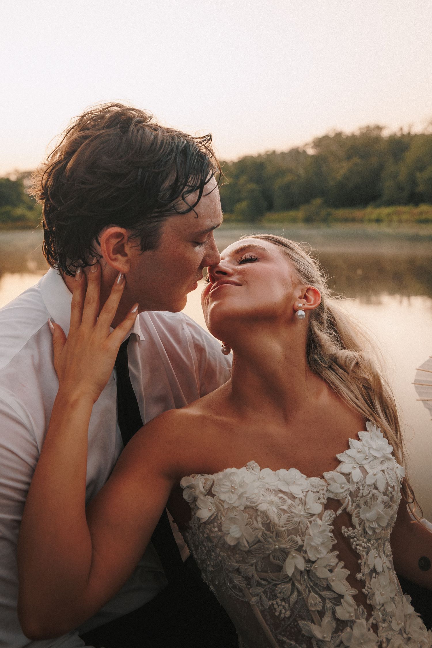 A tender golden hour moment between newlyweds by a serene lake.