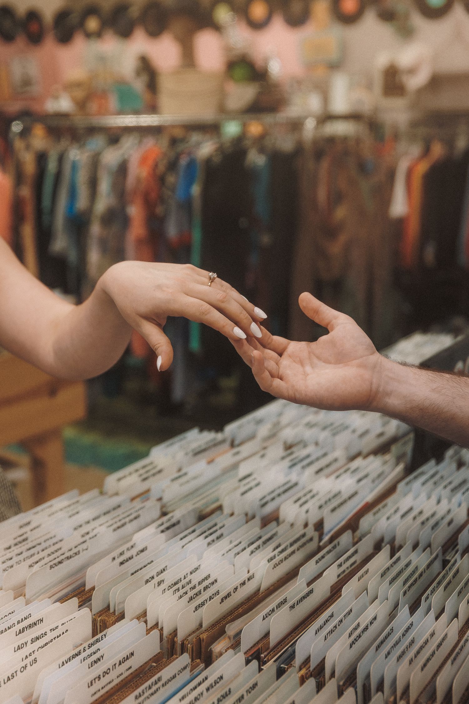 Hands browsing through organized record albums in vinyl collection storage at a vintage music store.