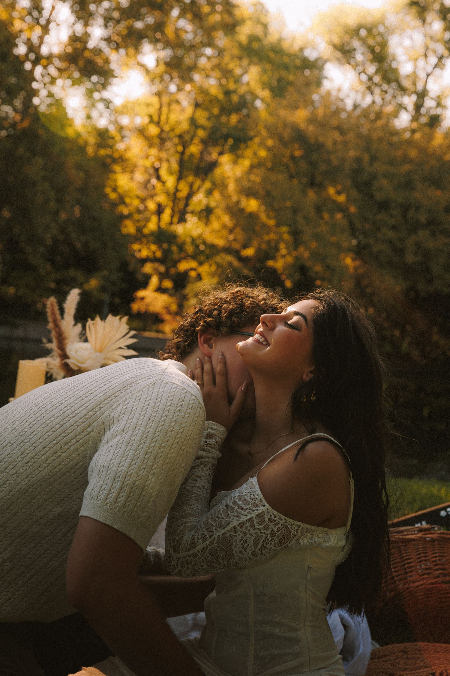 Couple sharing an intimate moment on a picnic blanket during sunset.