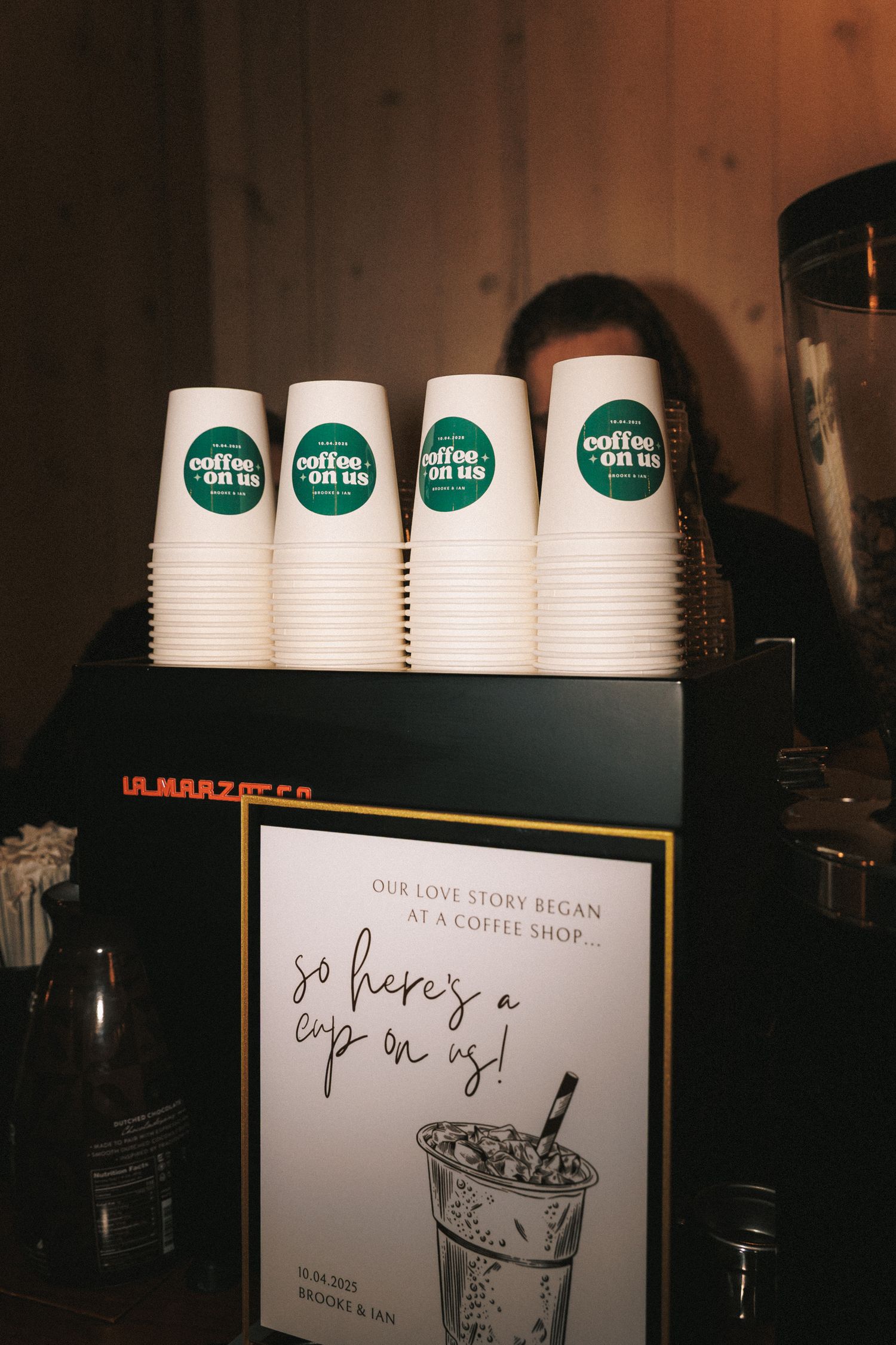 Custom coffee bar station with branded cups reading coffee on us at wedding reception.
