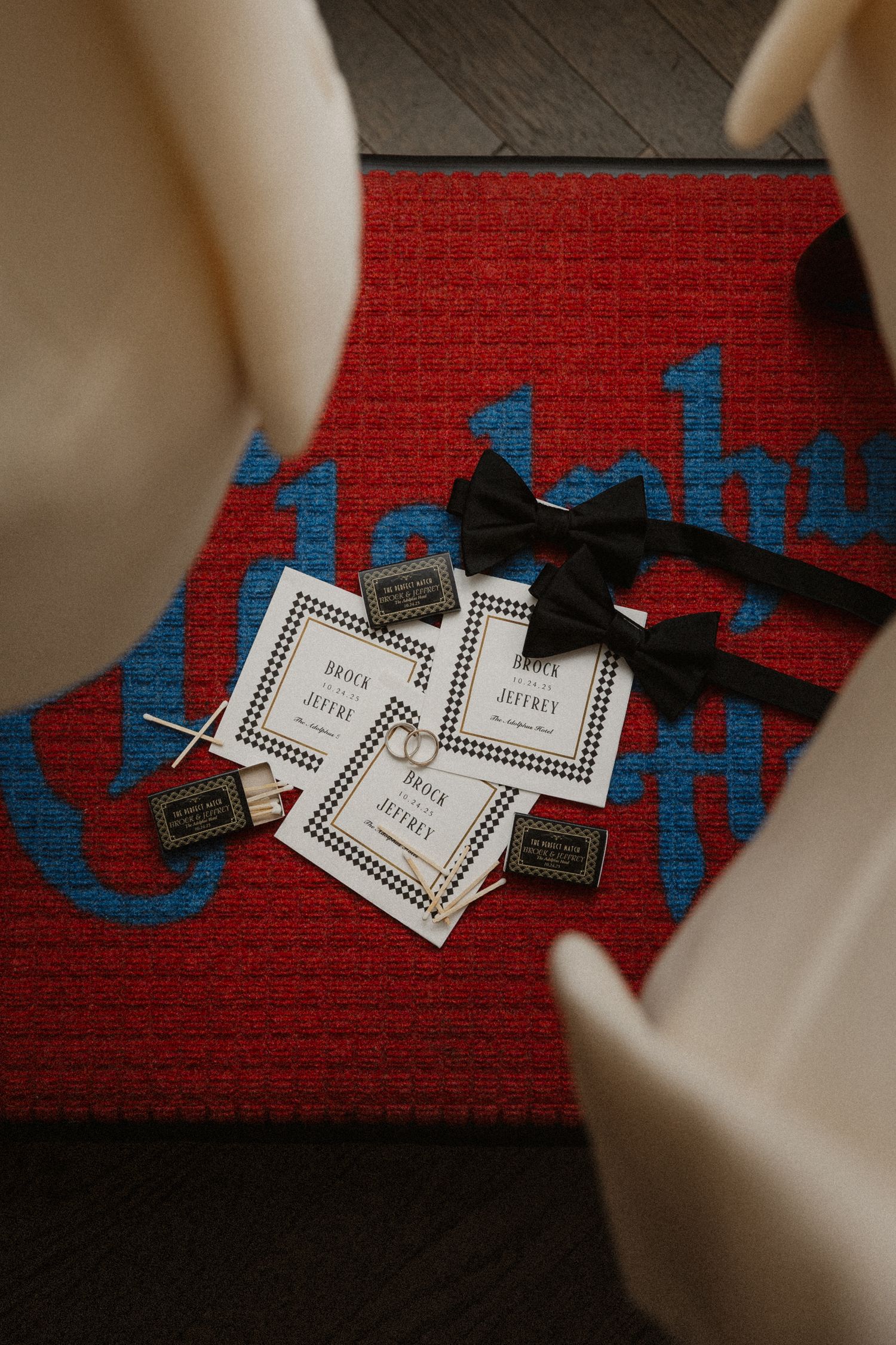 Black bow ties and wedding programs with matchboxes displayed on a red logo mat for a stylish wedding preparation.