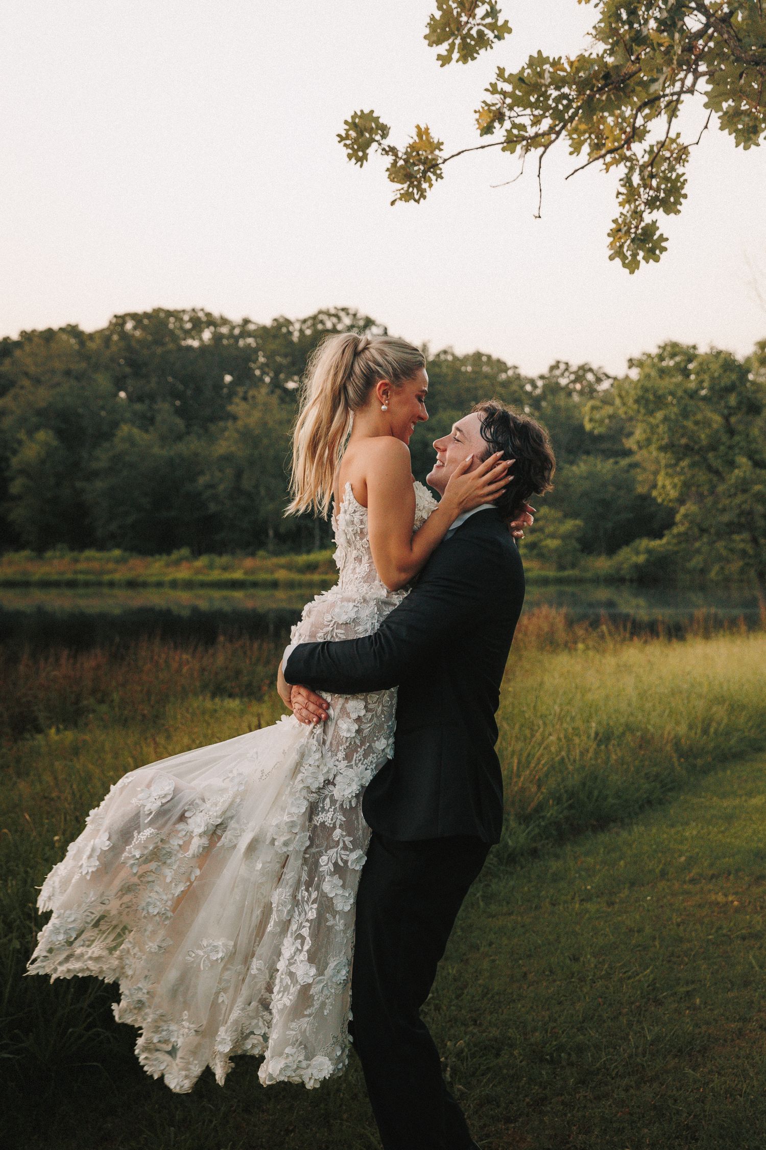 Romantic outdoor wedding photo shoot with dramatic dip pose in a natural setting.
