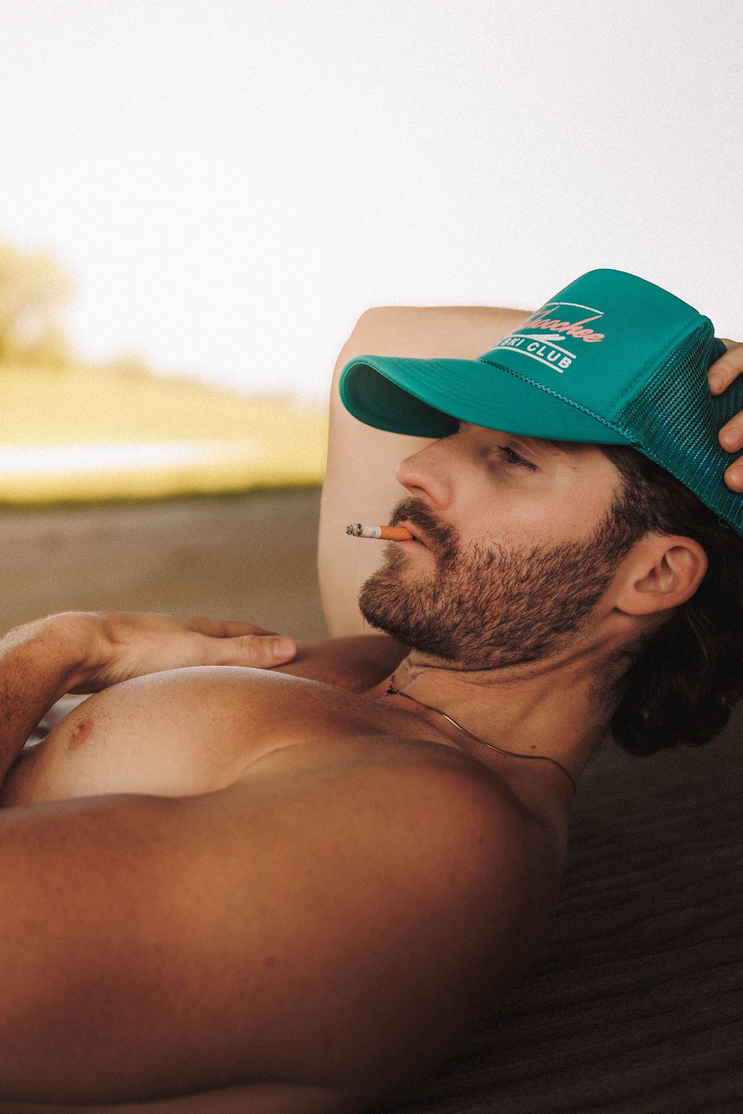 Person wearing a turquoise baseball cap lying down on a dark blanket or surface in a sequence of side profile shots.