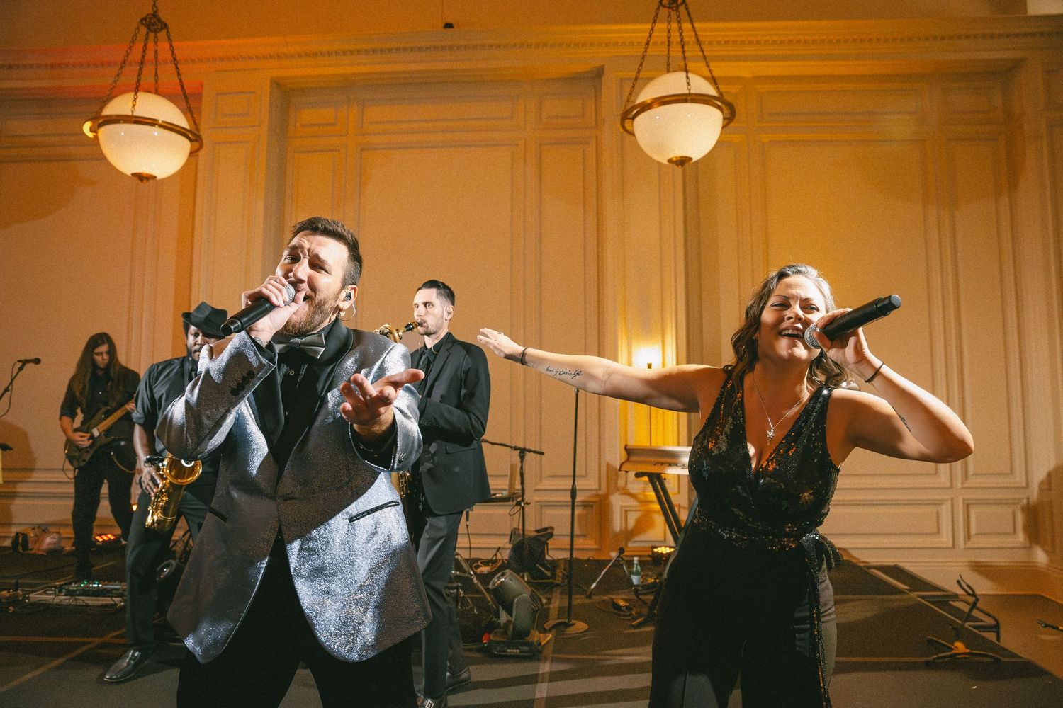 Live wedding band performs with male and female vocalists at elegant ballroom reception.