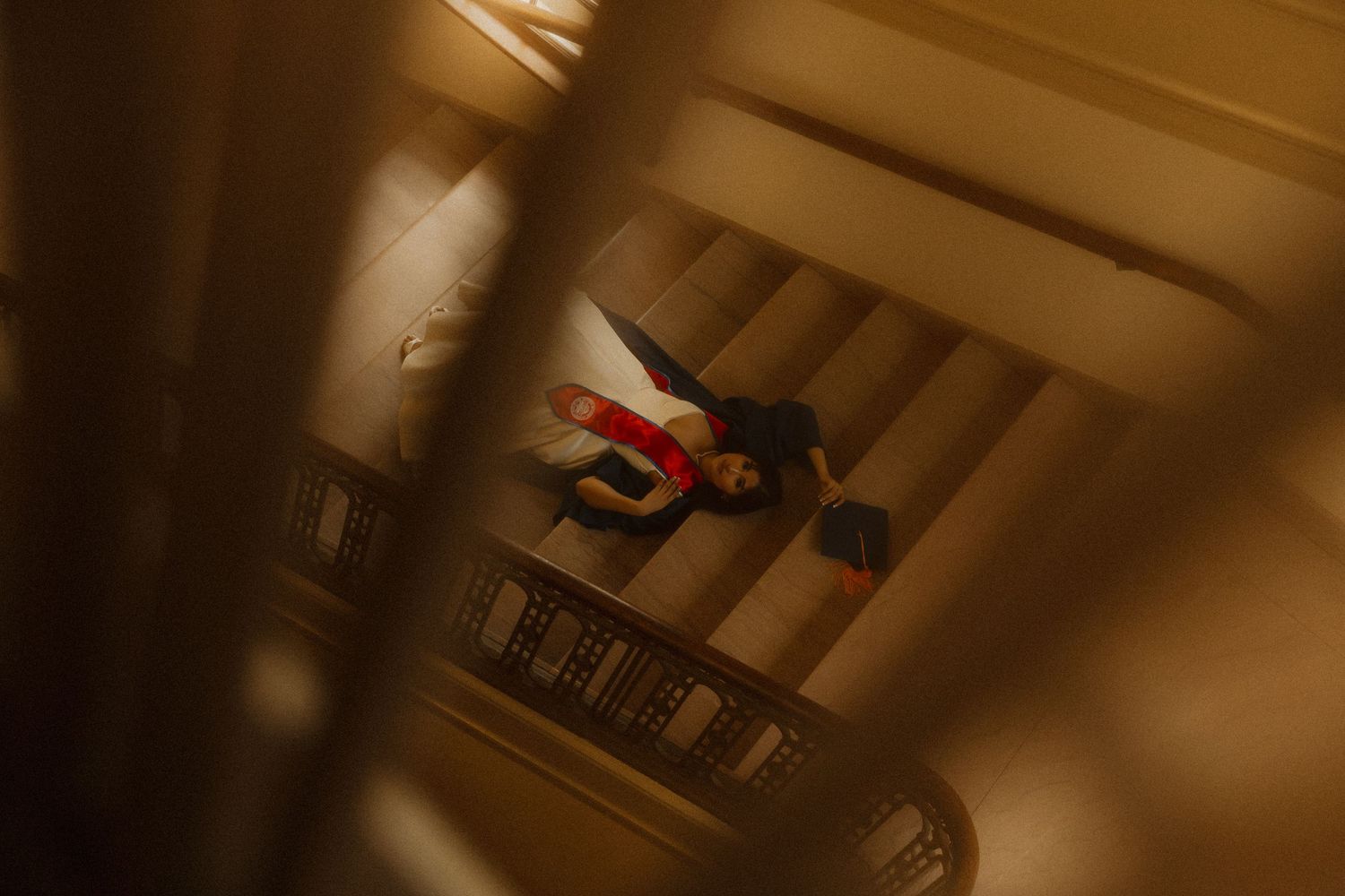 Person in red and black outfit captured from above on an ornate golden staircase interior.