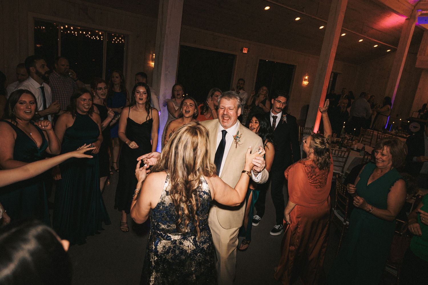 Couple shares a dance surrounded by guests on the wedding reception dance floor.