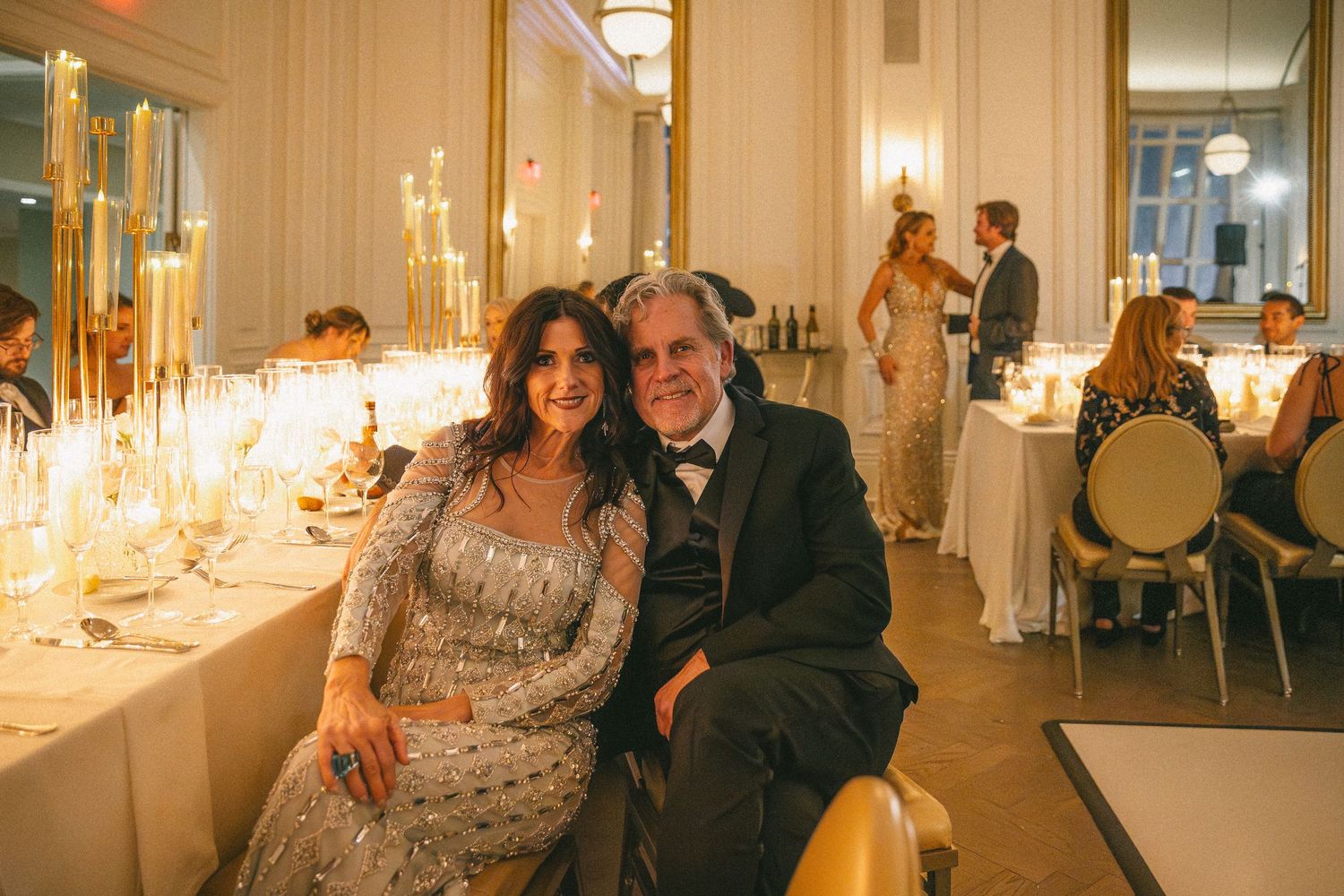 A smiling couple poses together at an elegantly candlelit wedding reception dinner.