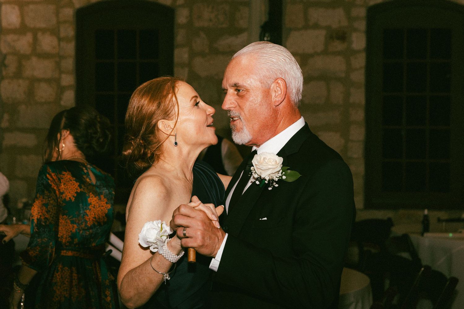 Father-daughter dance at wedding reception, older man in tuxedo dancing with woman in navy dress.