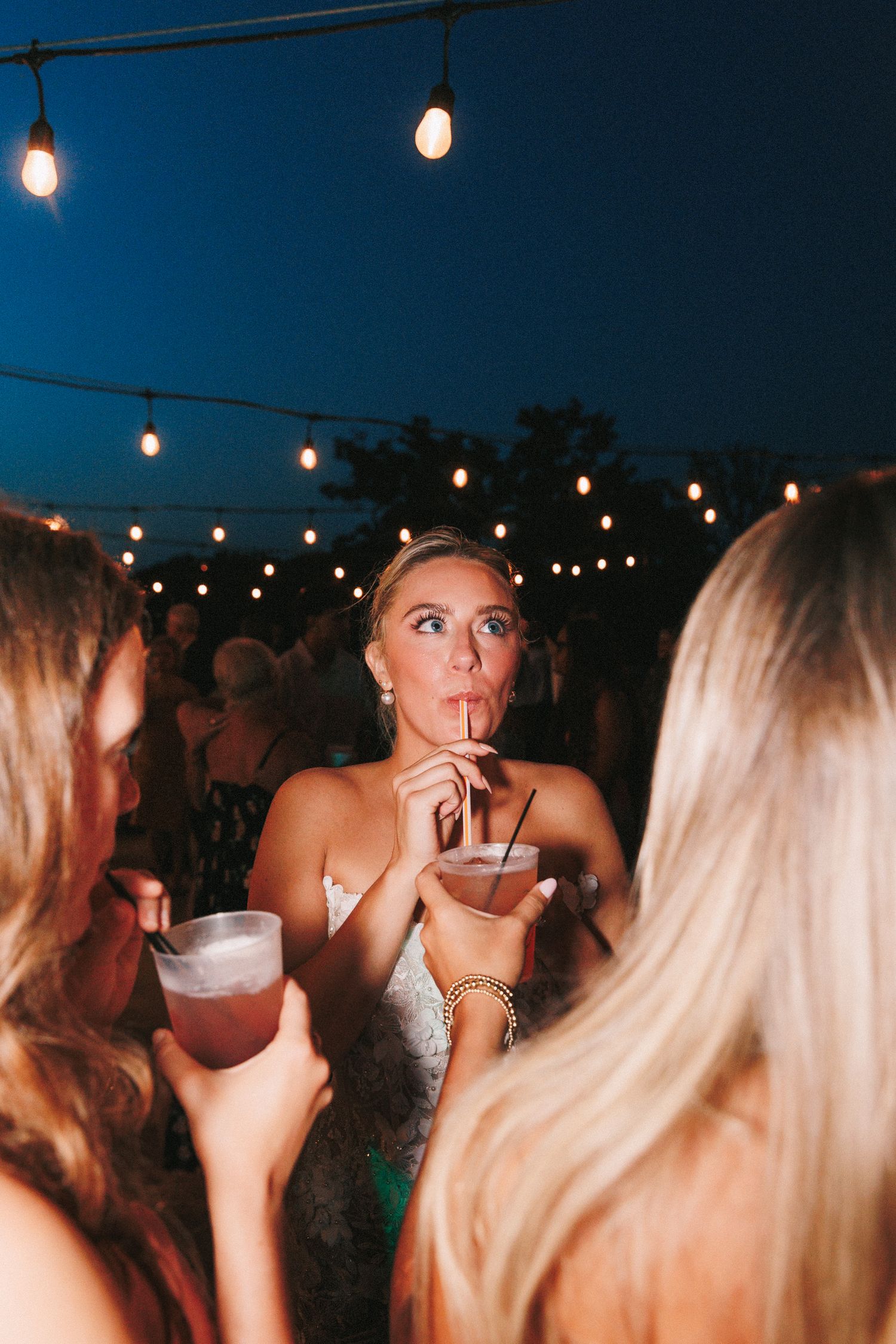 Wedding reception string lights illuminate an evening outdoor celebration.