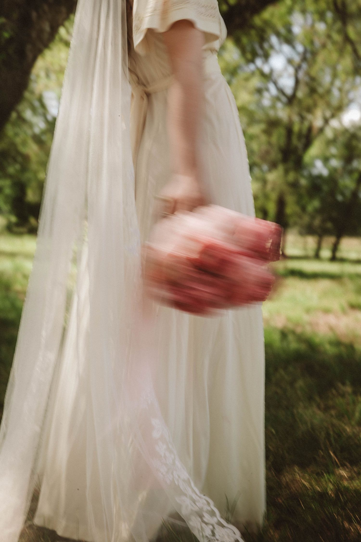 A flowing white dress moves gracefully in the wind as someone spins in an outdoor garden setting.
