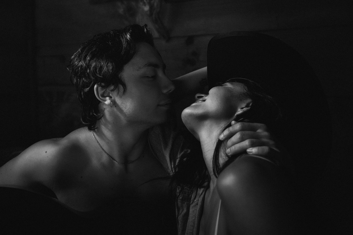 Intimate black and white close-ups of a couple sharing romantic kisses in moody lighting.
