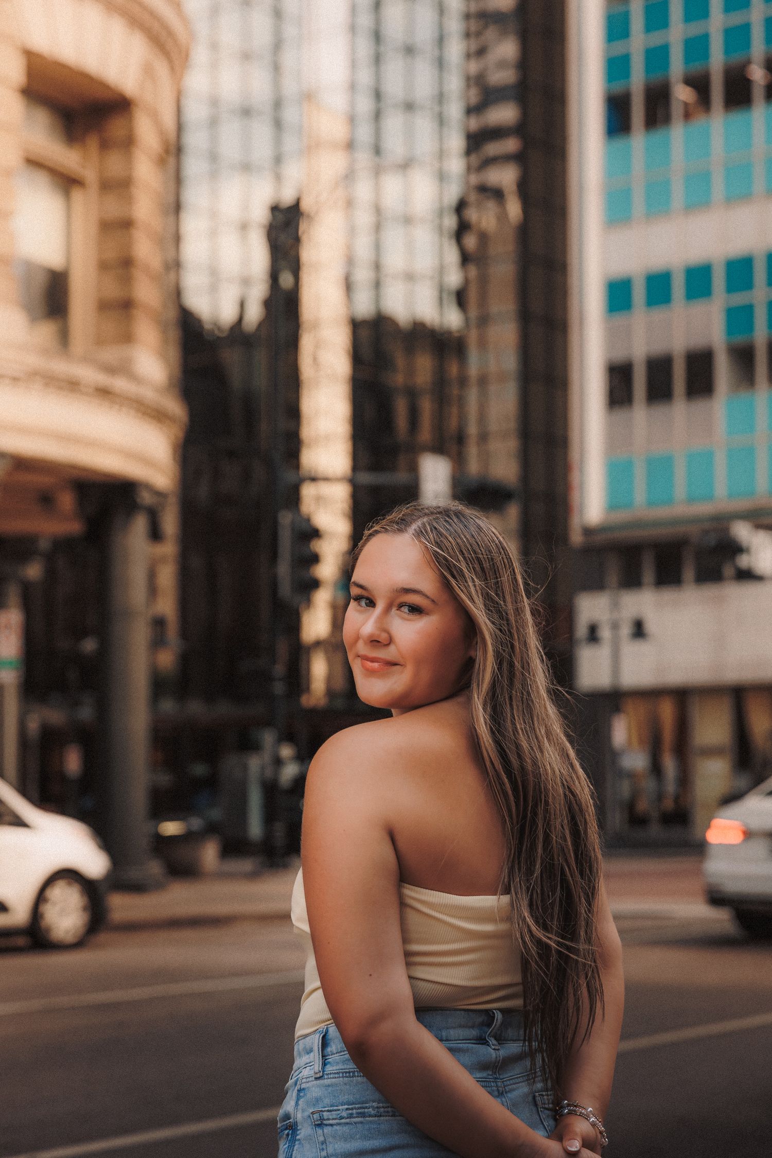 Urban street portrait with modern buildings and warm evening lighting.