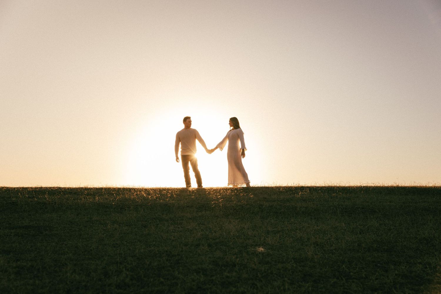 Silhouettes of people walking hand in hand along a horizon at sunset creating a romantic scene.