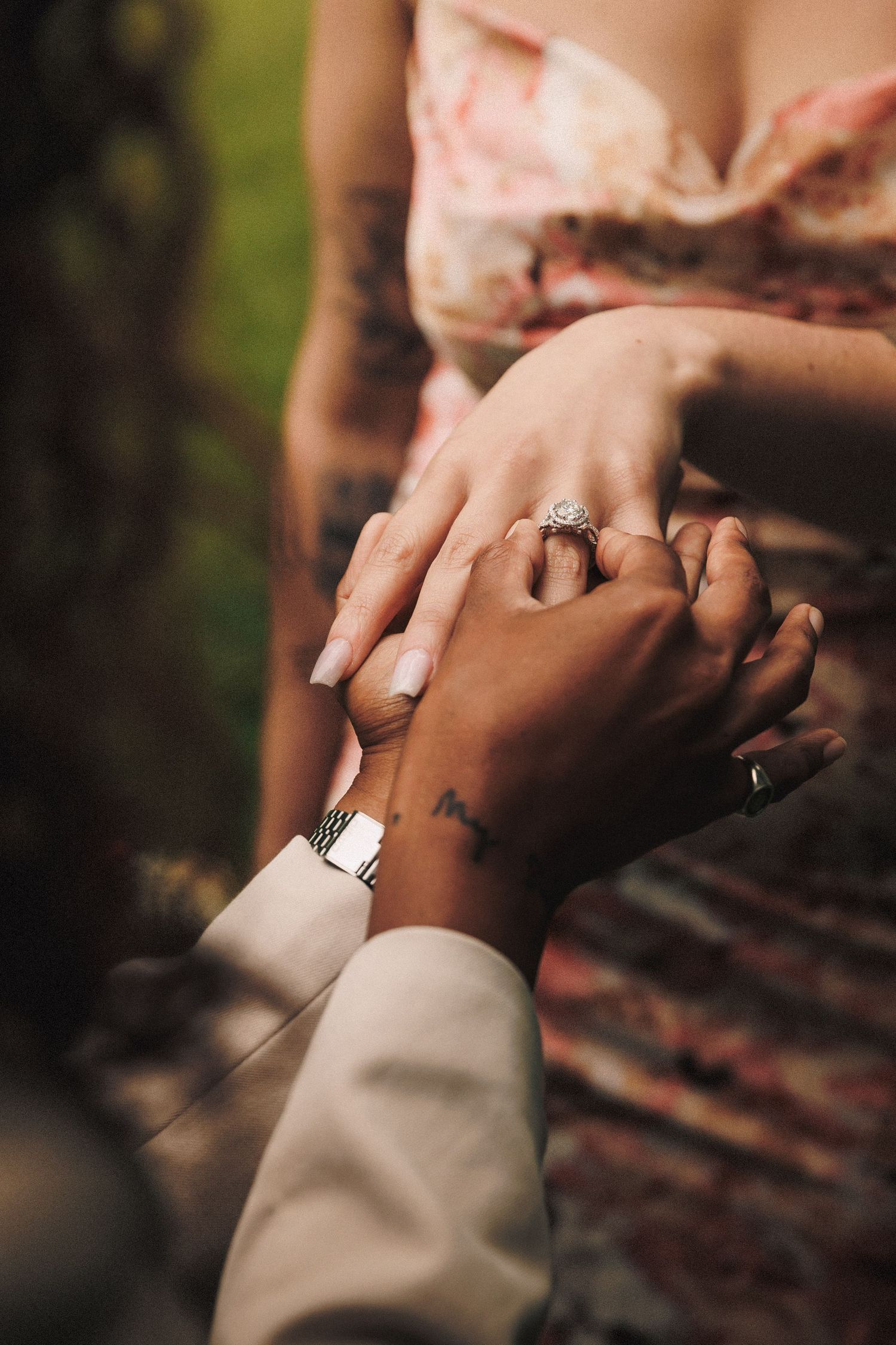 Two hands wearing wedding rings gently clasp together against a soft blurred background.