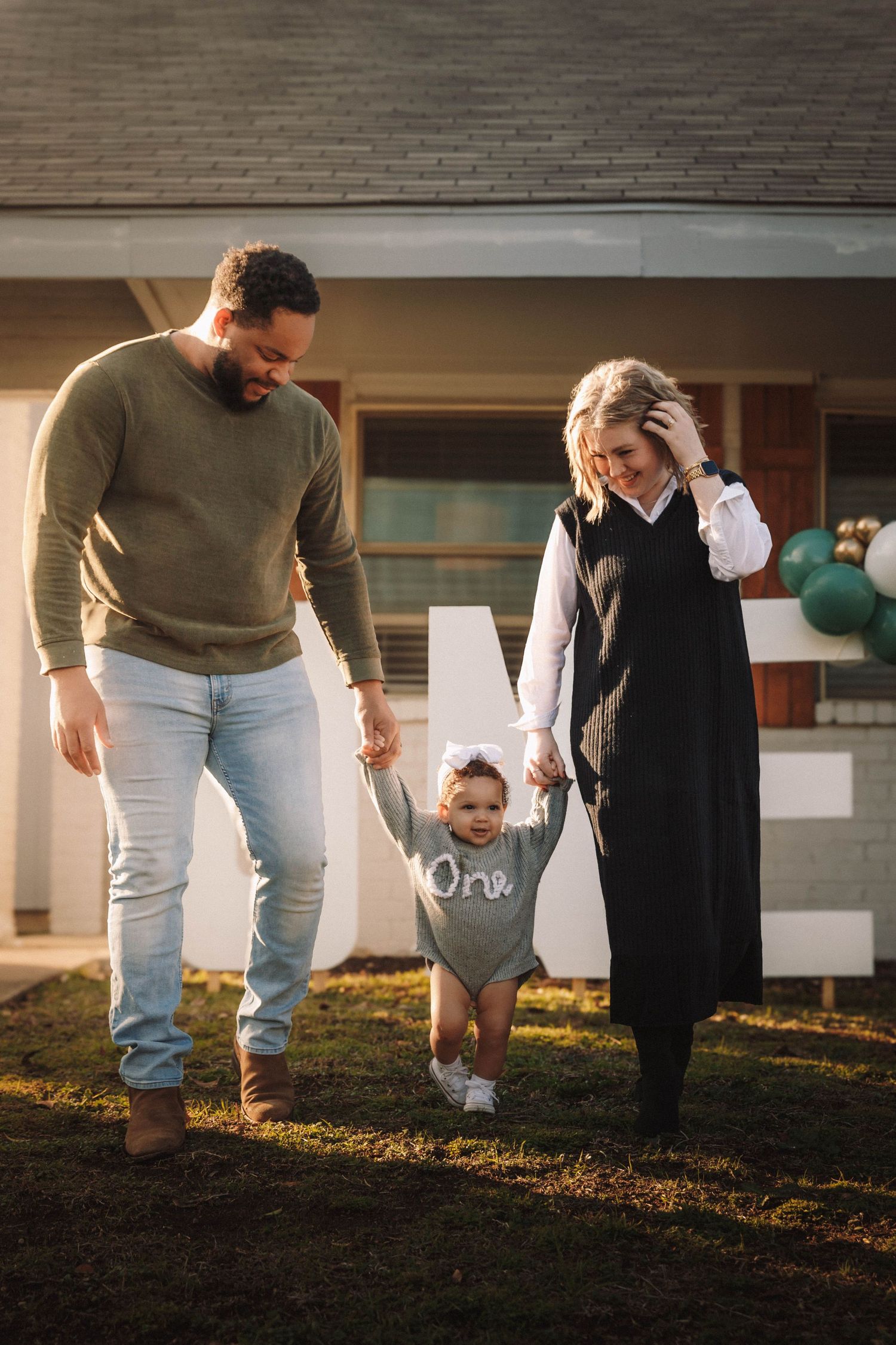 A family holding hands and walking together in the backyard during golden hour sunset lighting.