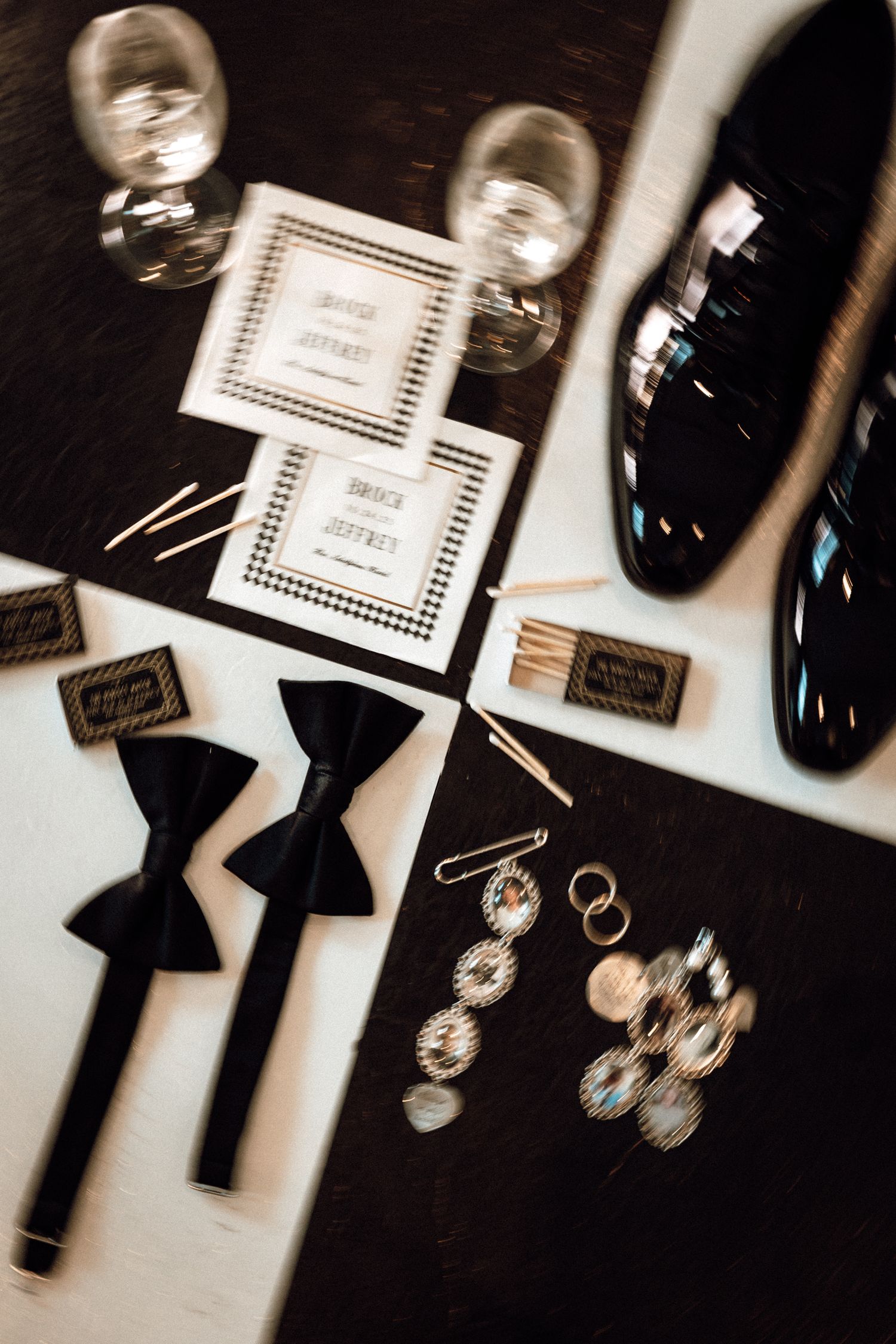 Elegant wedding flat lay with bow ties, dress shoes, invitations, and jeweled accessories.