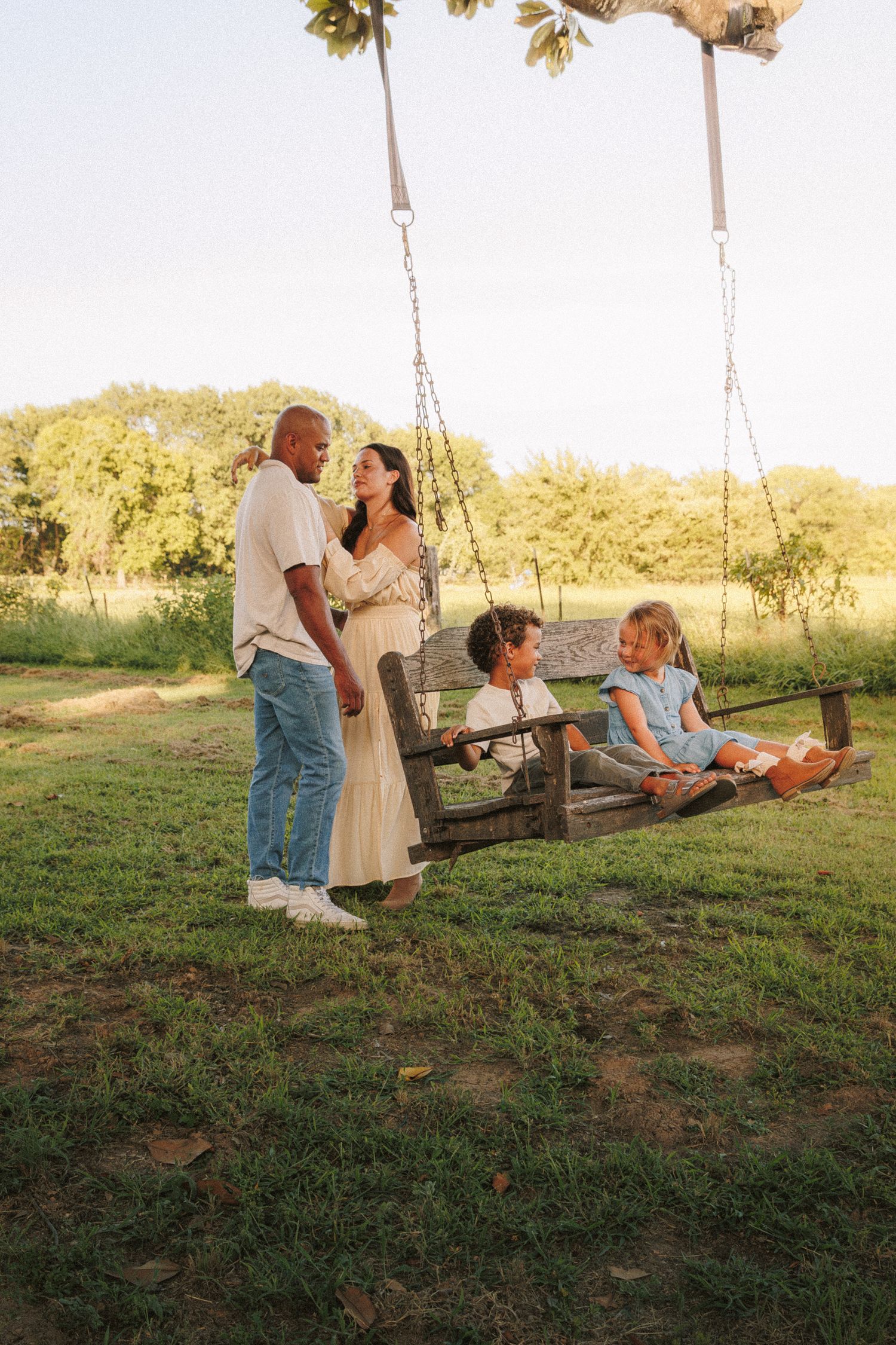 Family spending quality time together on tree swings in a scenic outdoor setting during golden hour.