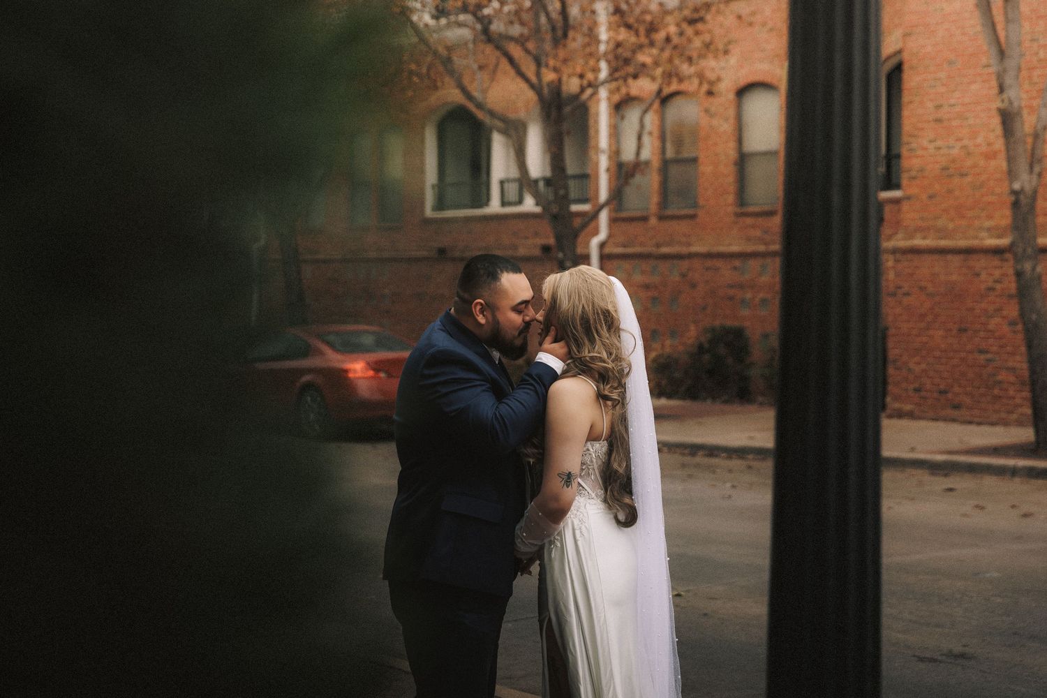 A couple shares a romantic moment in front of a brick building during a golden hour photo session.