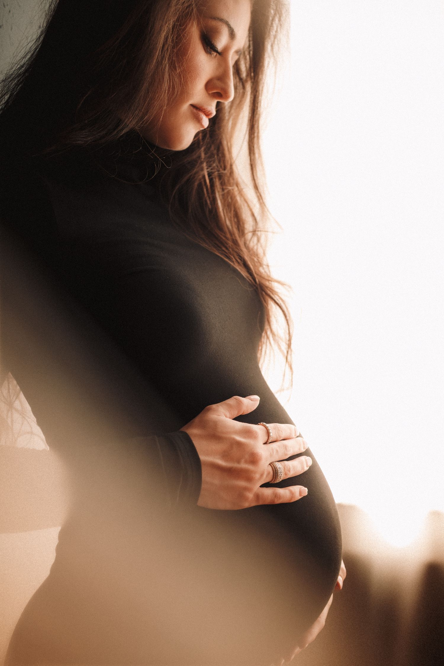 Artistic maternity photo series showing silhouette in black against warm light background.