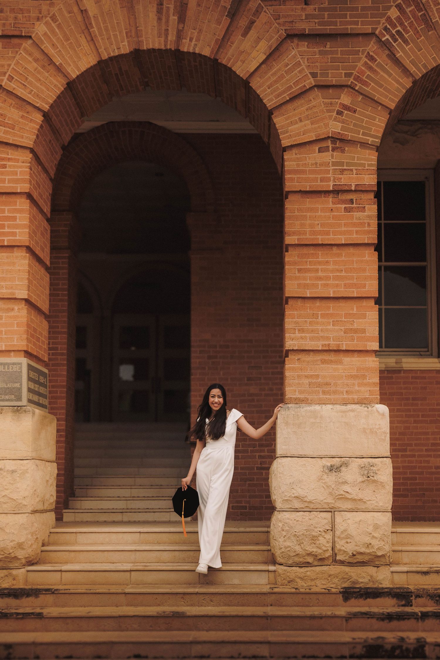 Figure in white moves gracefully through a series of brick archways during a photo sequence in warm lighting.