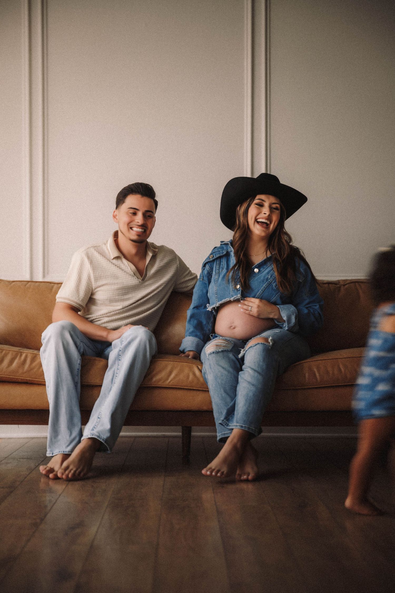 Couple sitting together on brown leather couch laughing and sharing candid playful moments in series of photos.