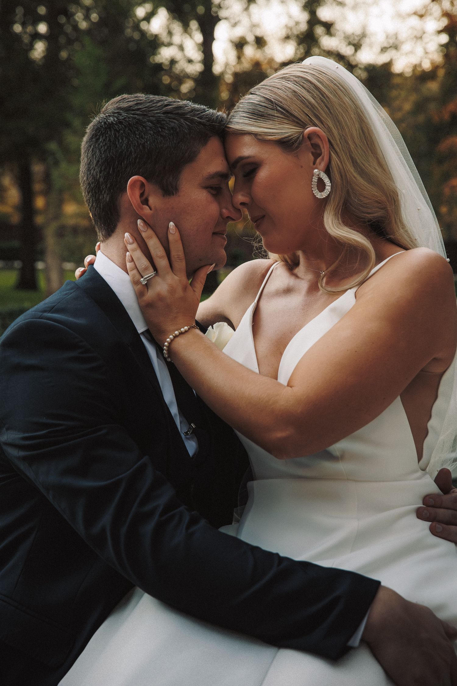 Bride and groom share intimate forehead touch moment in golden outdoor light.