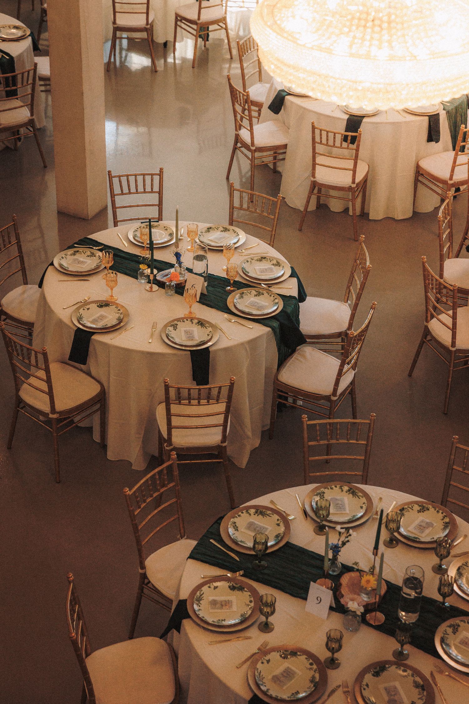 Aerial view of elegantly set round wedding reception tables with gold chiavari chairs.