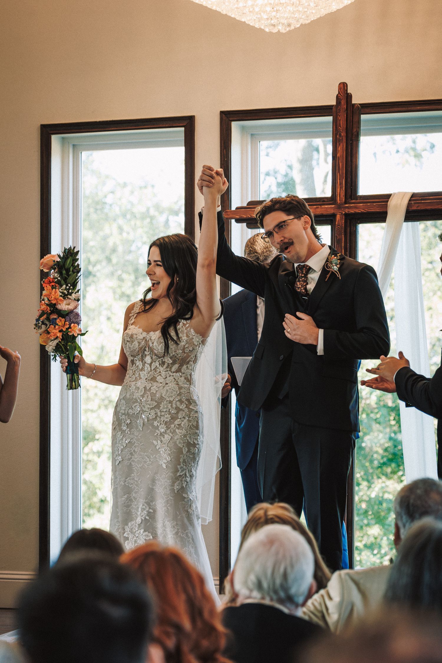 Joyful bride and groom raising hands in celebration at the altar after their wedding ceremony.