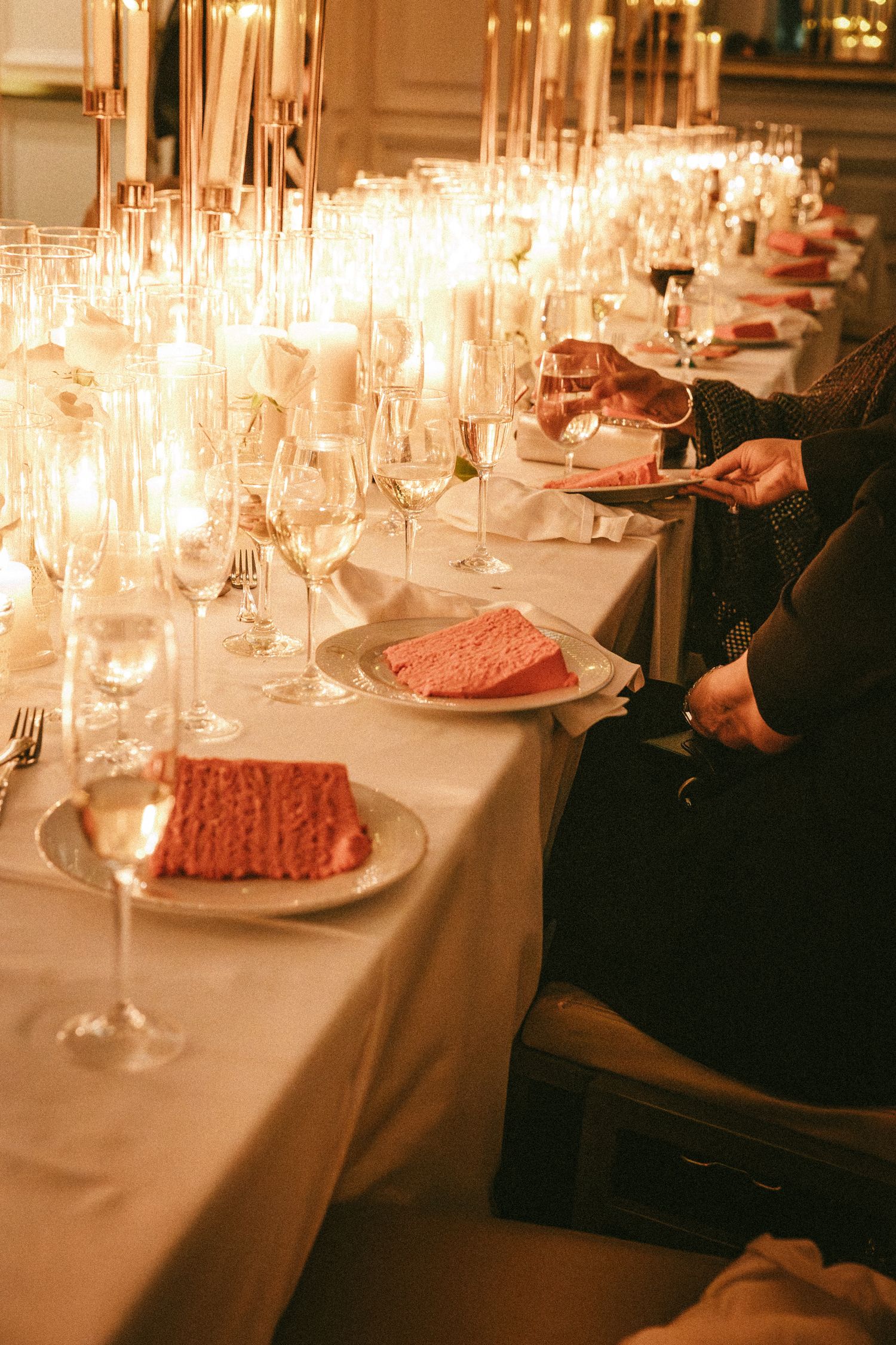 Elegant wedding reception table with pink napkins, champagne flutes, and candles.