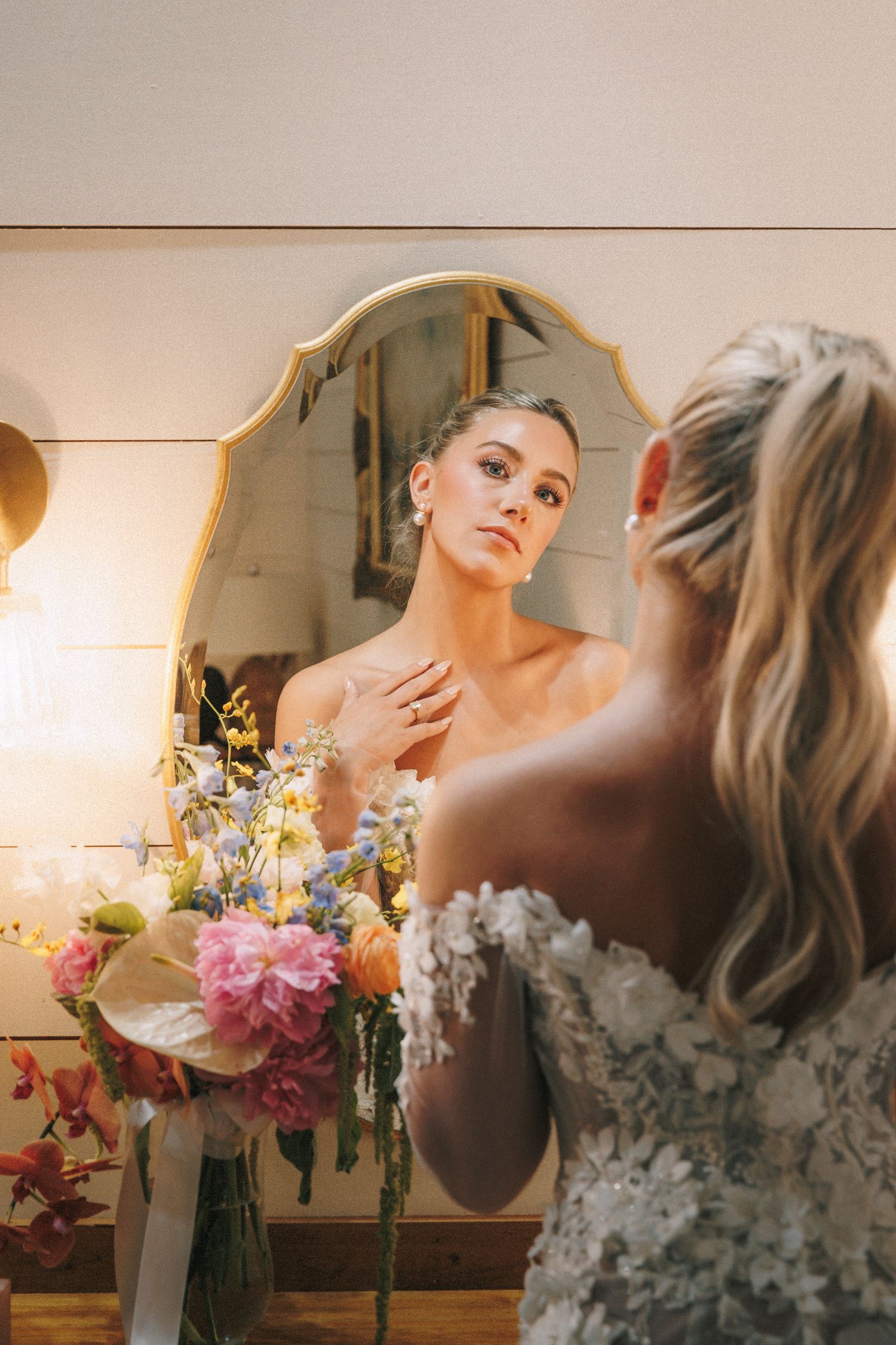 Wedding preparations with floral arrangements and mirror reflections in warm lighting.