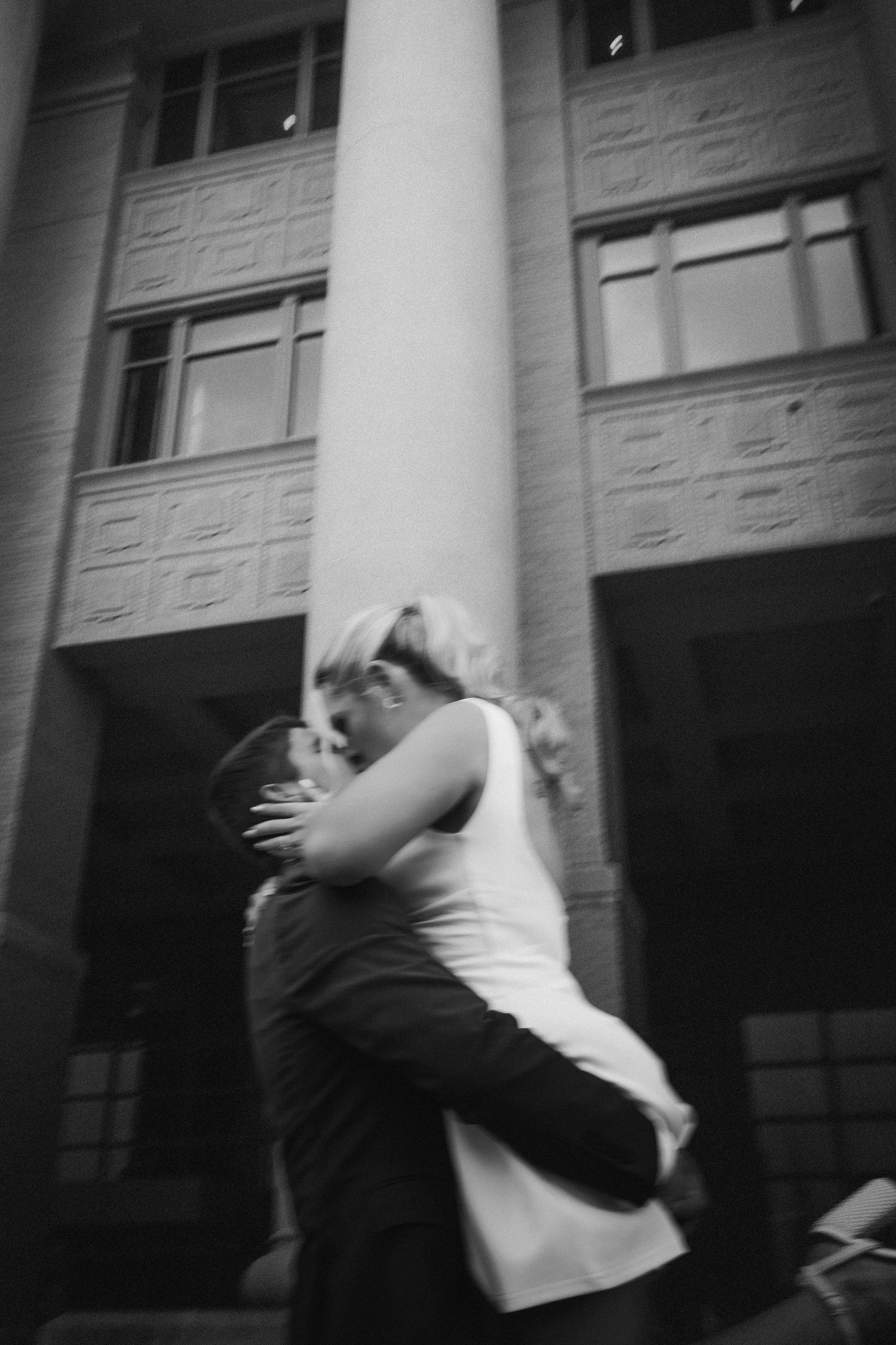 A sequence of black and white photographs showing a couple performing a dramatic dance dip against a municipal building backdrop.