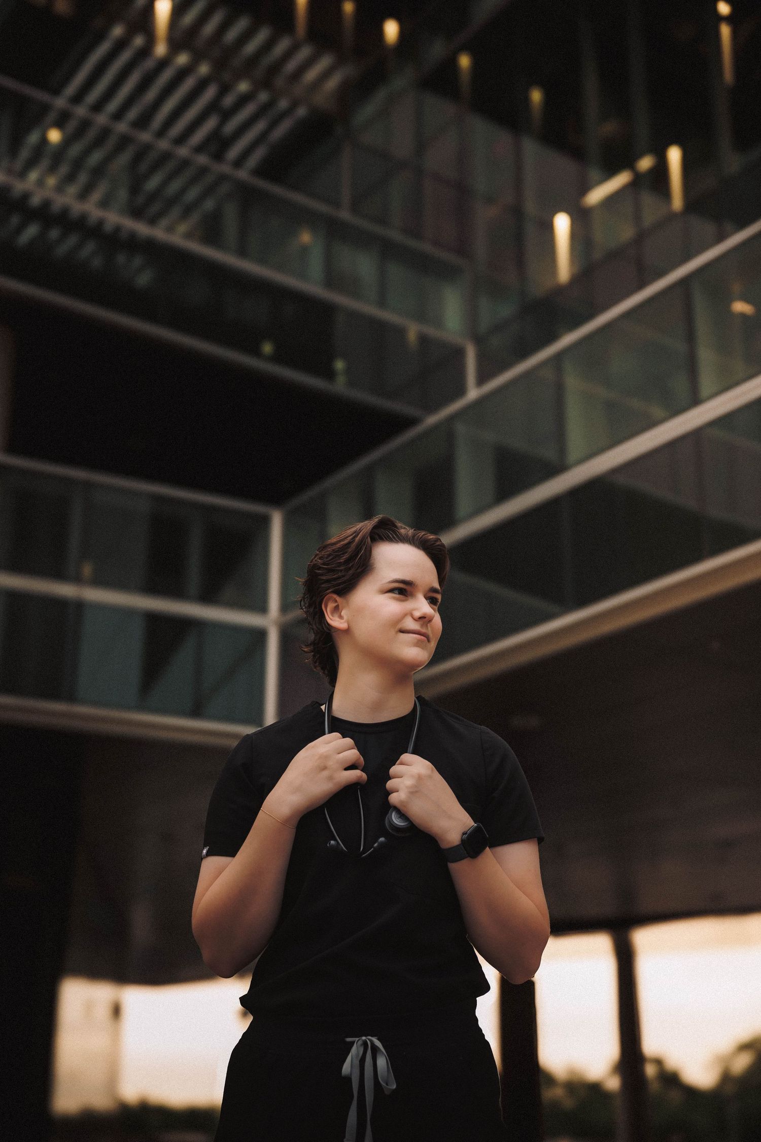 Person wearing black dress gazing thoughtfully into the distance in an architectural setting at sunset.