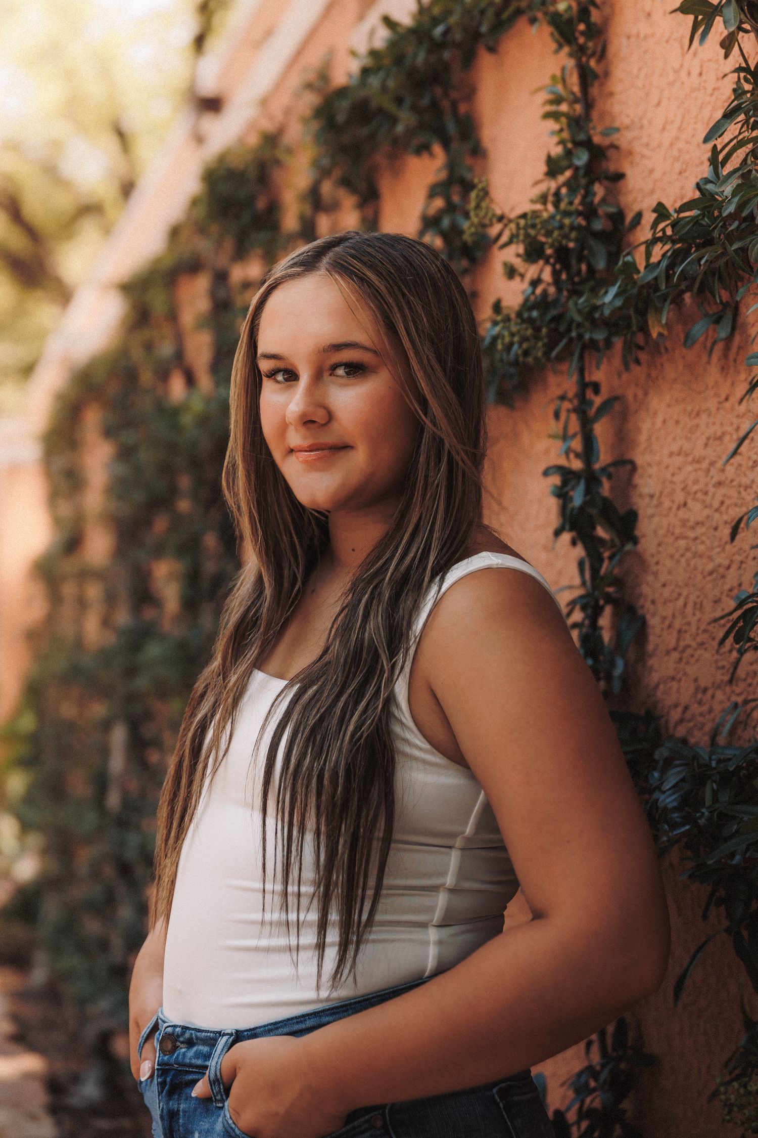 A series of outdoor portrait photos against a peach-colored wall with climbing ivy creating a natural backdrop.
