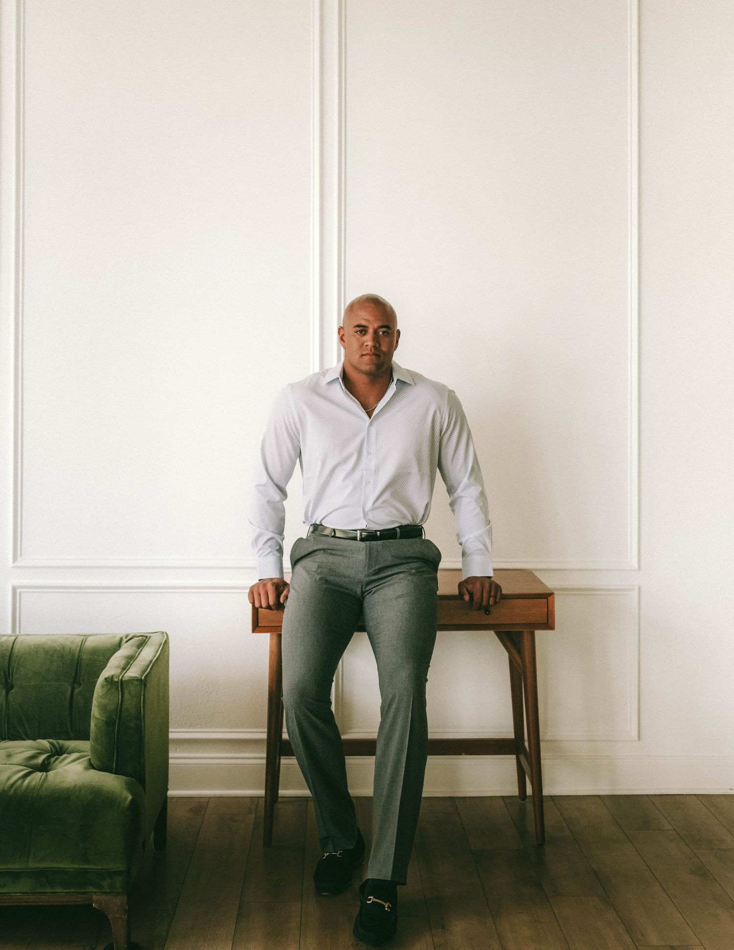 Minimalist portrait series showing someone seated on a wooden bench against a white wall with wood flooring.