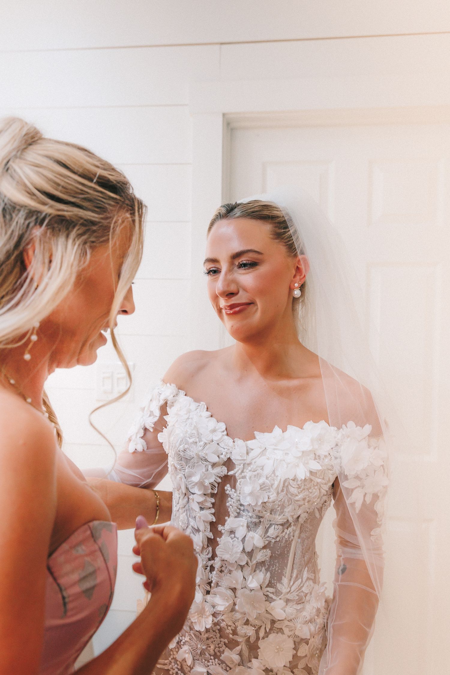 A bride in an ornate white lace dress laughs during candid moments before the ceremony.