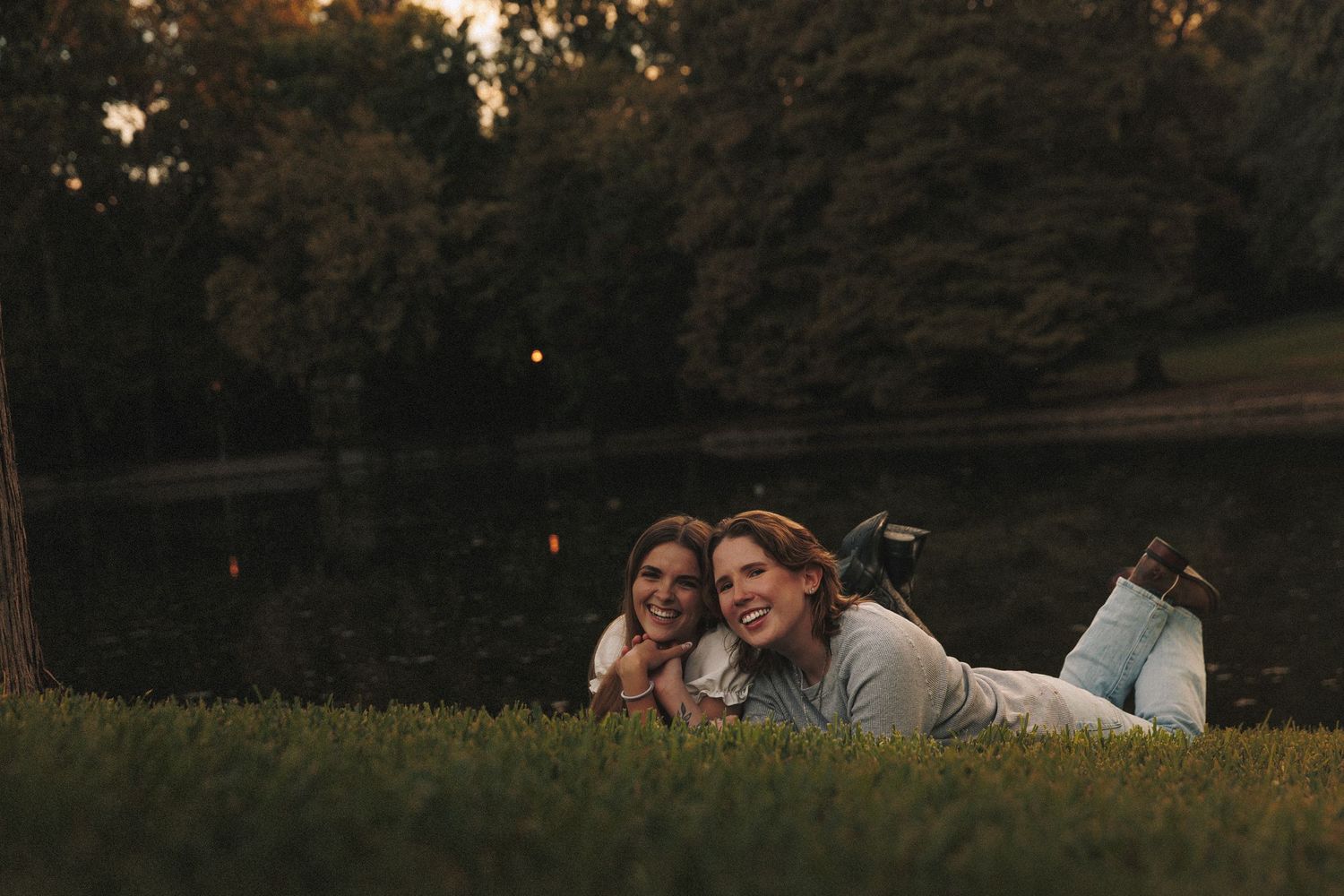 A romantic couple embraces in a dreamy outdoor setting at sunset with golden light filtering through trees.