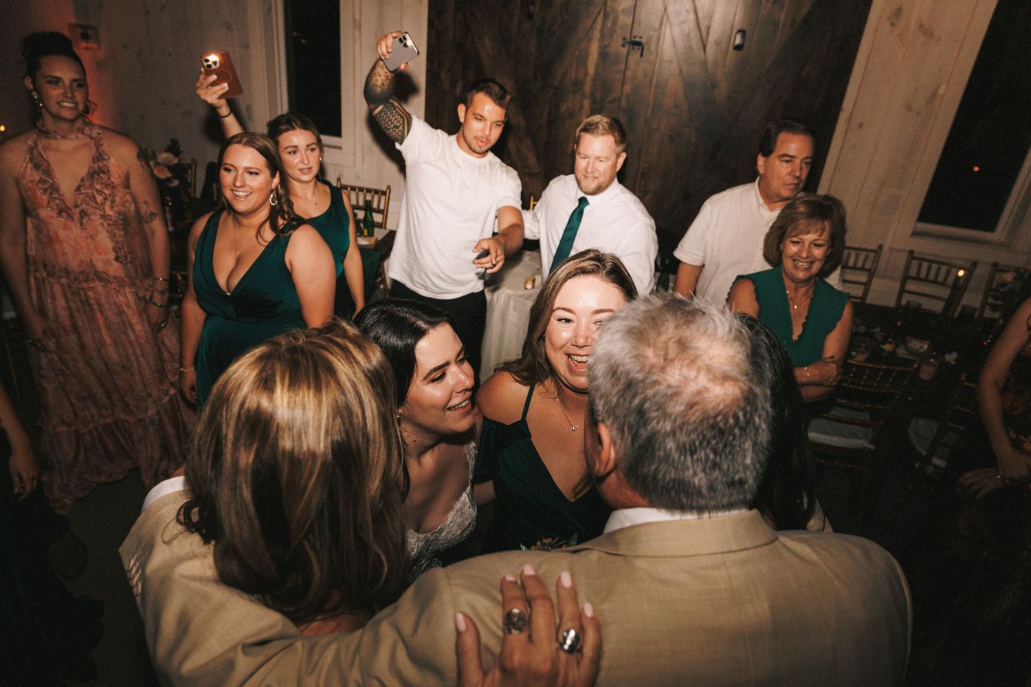 Wedding guests dance and celebrate joyfully together on the reception dance floor at night.